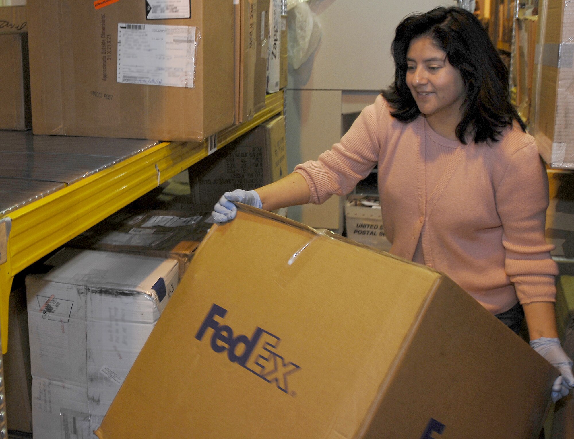 Post office volunteer Violeta Musseb-Gil organizes packages delivered to the post office.   (Photo by Airman 1st Class Liliana Moreno)