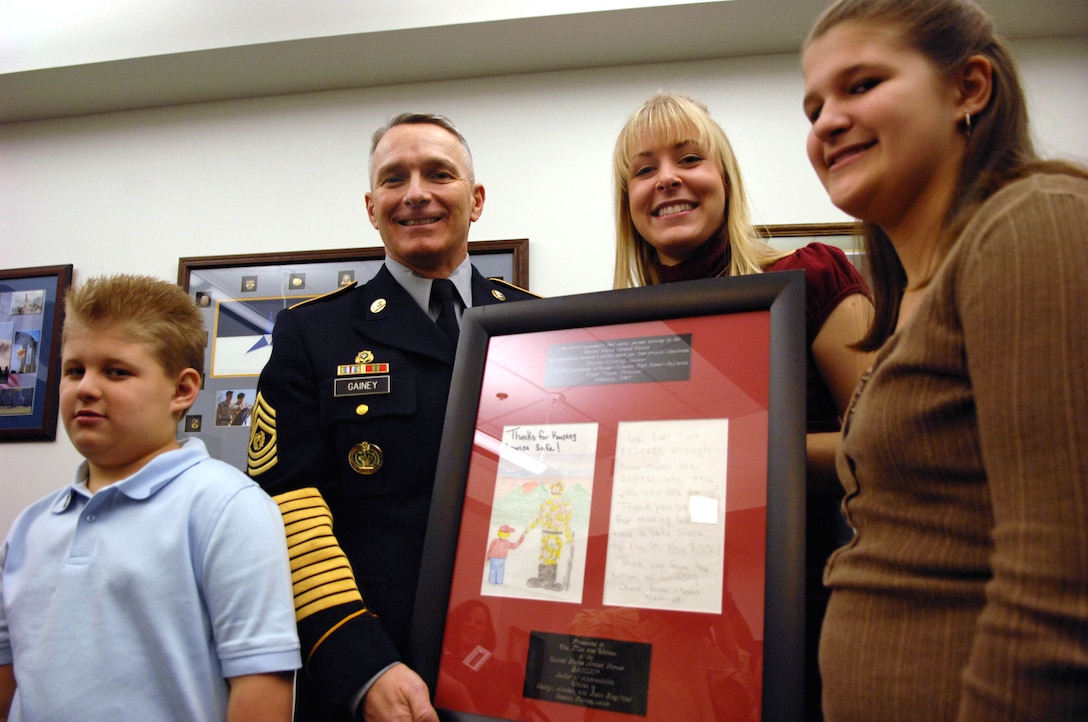Shauna Fleming, founder of A Million Thanks, (center right) presents Army Sgt. Maj. William J. Gainey, the senior enlisted advisor to the chairman of the Joint Chiefs of Staff, the 2.6 millionth letter her organization collected in a Feb. 1 ceremony at the Pentagon. The milestone letter was written by Amber Siegfried, 12, (right) and her brother, Sean, 8. Photo by William D. Moss