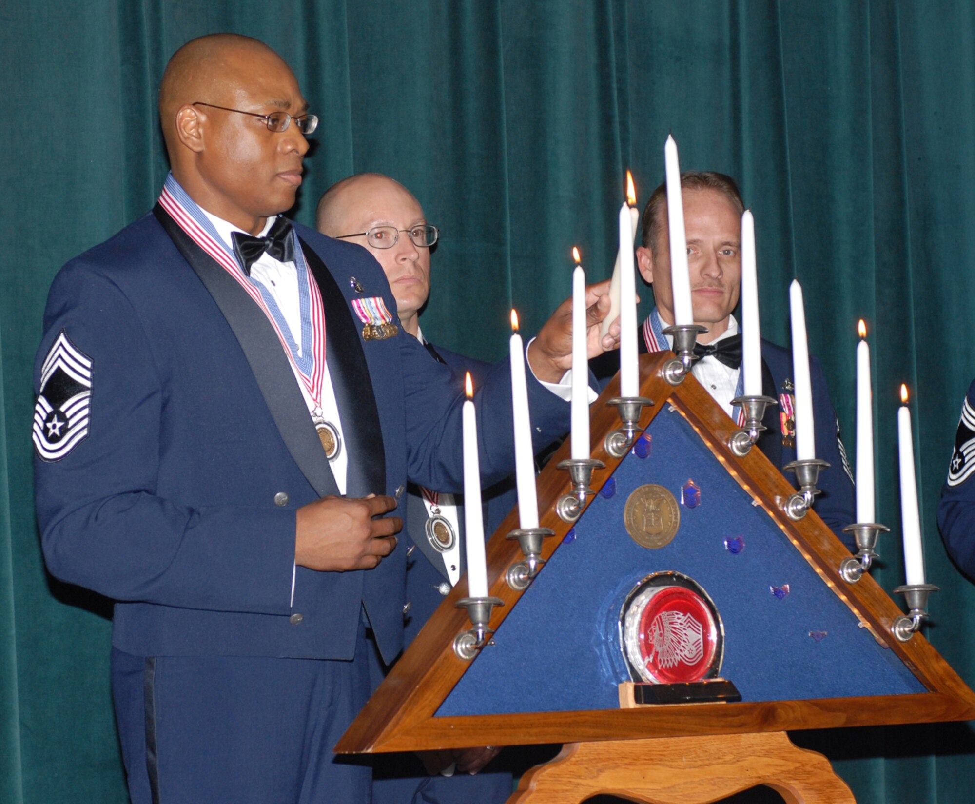 Chief Master Sgt. Ronald Ward, left, 56th Medical Operations Squadron Lab Flight superintendent, lights a candle in the candle lighting ceremony during the Chiefs Induction ceremony Jan. 26 at the Desert Star Club. Also pictured are chief
selects, Senior Master Sgt. Patrick Wilson, center, 56th Security Forces Squadron superintendent, and Senior Master Sgt. Michael Smith, 56th Logistics Readiness Squadron Fuels manager.  Photo by Senior Airman Christopher Hummel