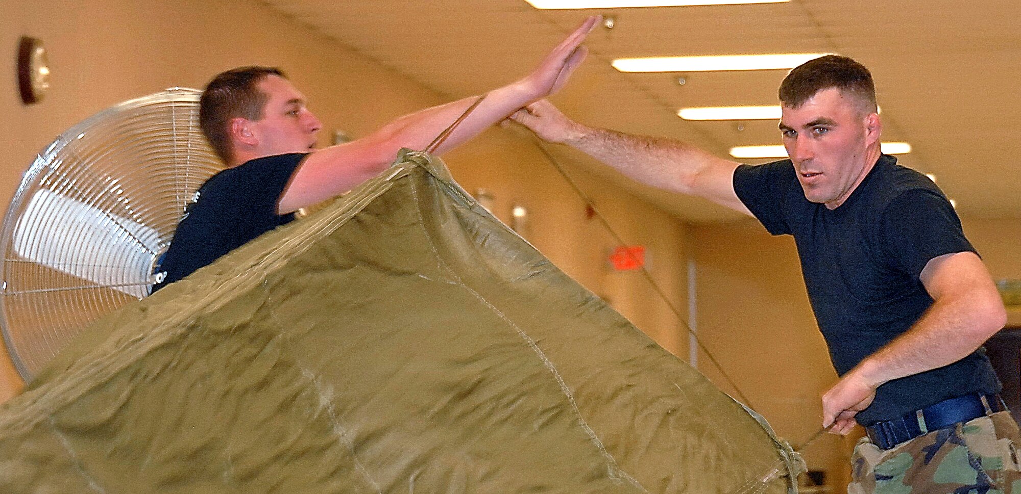 Staff Sgt. Ross McCormick and Airman 1st Class Ryan Stoks prepare a parachute for folding. Airman Stoks says he learned to become a strong leader and individual while wrestling in high school and college, which helps him in the Air Force. (U.S. Air Force photo by Laurence Zankowski)