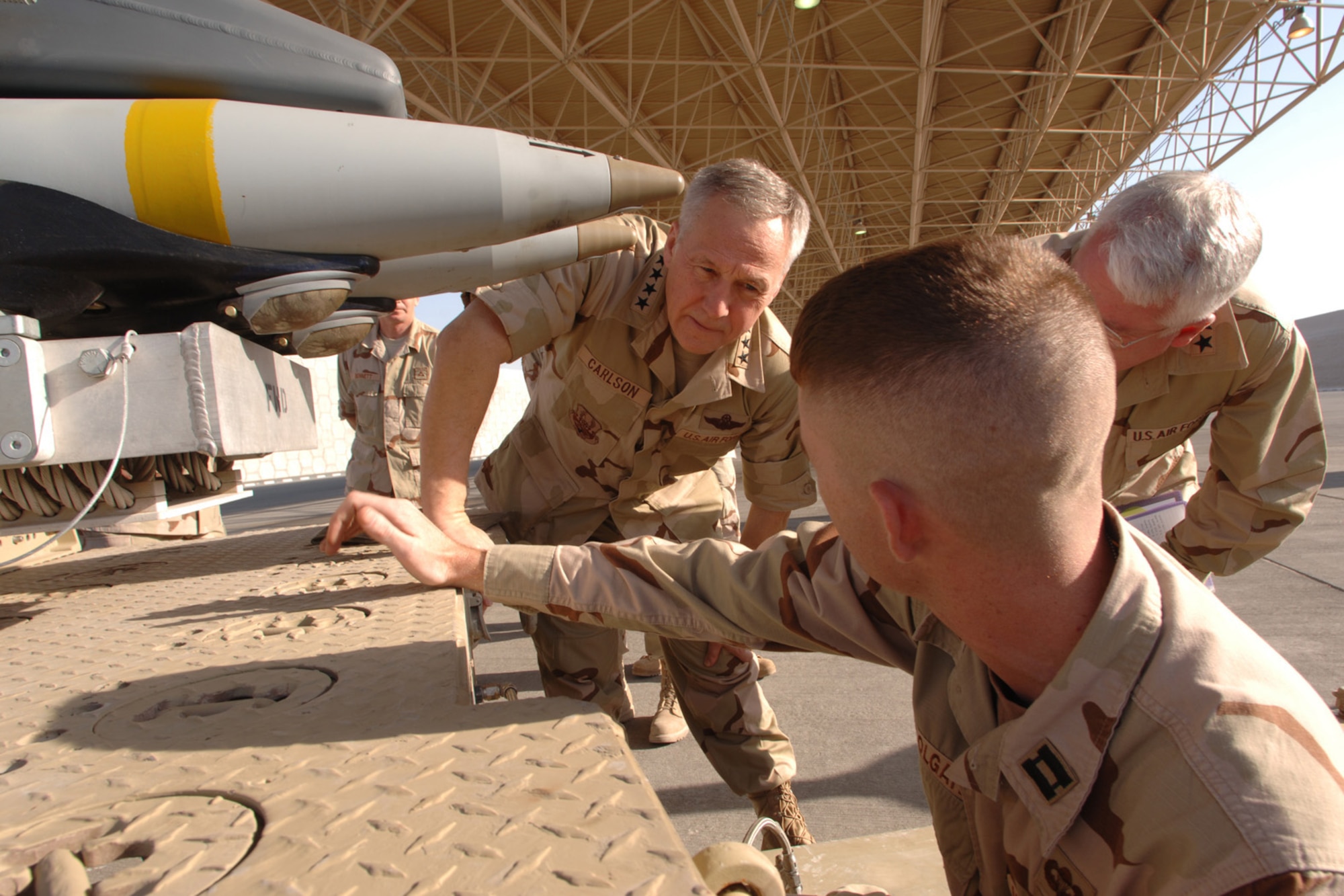 Gen. Bruce Carlson and Maj. Gen. Arthur B. Morrill III tour a desert base where they are briefed by Capt. Shad Colgate on the functionality of the Air Force's newest munition -- the 250-pound small diameter bomb on a Jan. 24 visit to Southwest Asia. General Carlson is the commander of Air Force Materiel Command. General Morrill is the AFMC Logistics Director. Captain Colgate is deployed from Lakenheath Air Base, England, as officer in charge of the 494th Expeditionary Maintenance Squadron's Munitions Flight. (U.S. Air Force photo/Master Sgt. Scott Wagers) 
