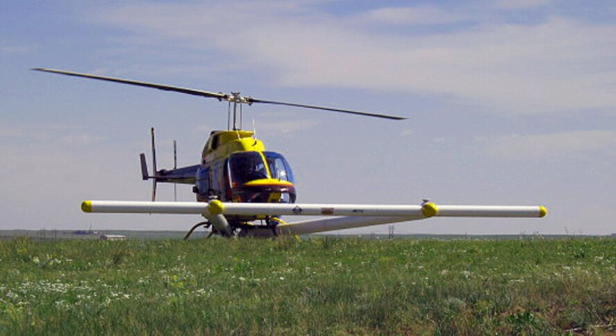 A helicopter with a metal detector mounted on it rests in a field. A helicopter such as this one will be flying over areas of Kirtland that were once used for munitions operations in the past. The helicopter will be searching for unexploded munitions and other debris. (Courtesy photo)