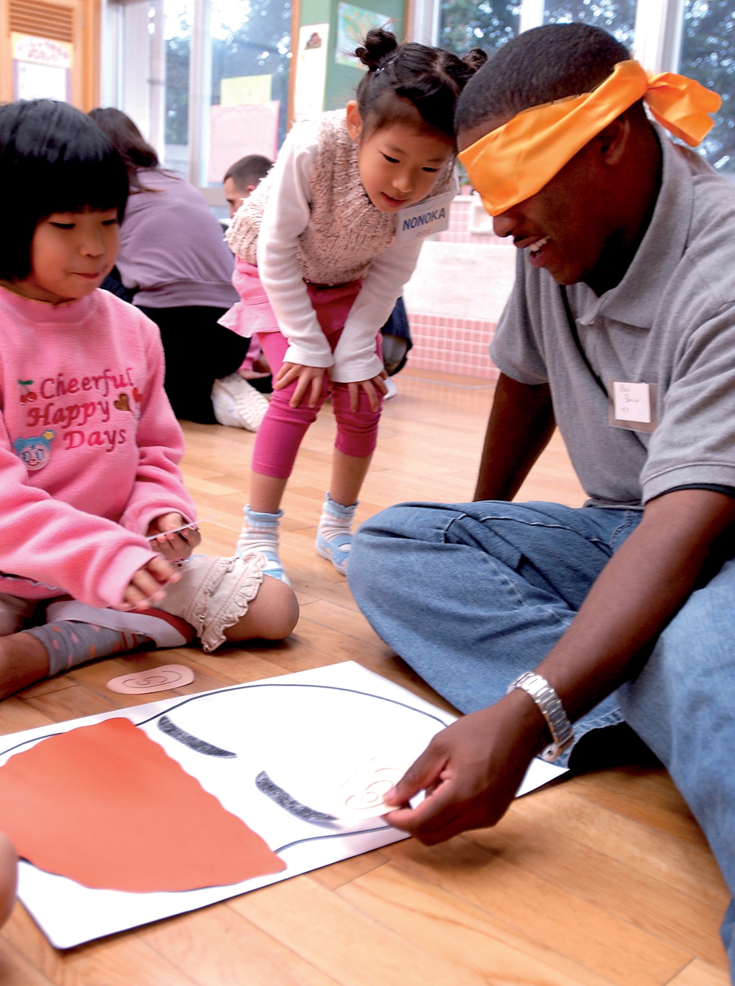 KADENA AIR BASE, Japan -- Senior Airman Mark Barrow, 18th Component Maintenance Squadron, plays a game with Okinawan children. The game teaches children the features of a face in English and Japanese. (U.S. Air Force photo/Airman 1st Class Kelly Timney)