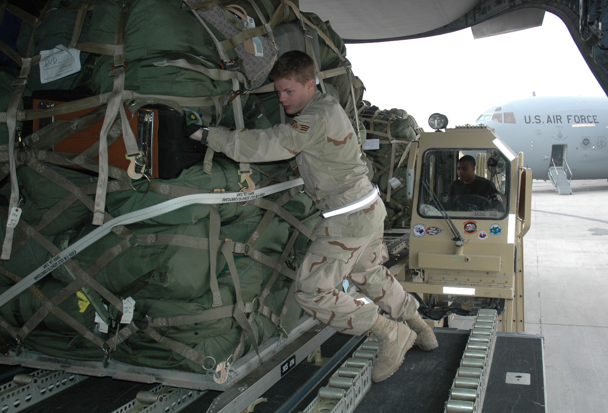 Senior Airman Aaron Brewer helps push a pallet into a C-17 Globemaster III while Airman 1st Class Armel Trollinger operates a 60K loader. Both are aerial porters assigned to the 8th Expeditionary Air Mobility Squadron. (U.S. Air Force photo\Senior Airman Erik Hofmeyer)