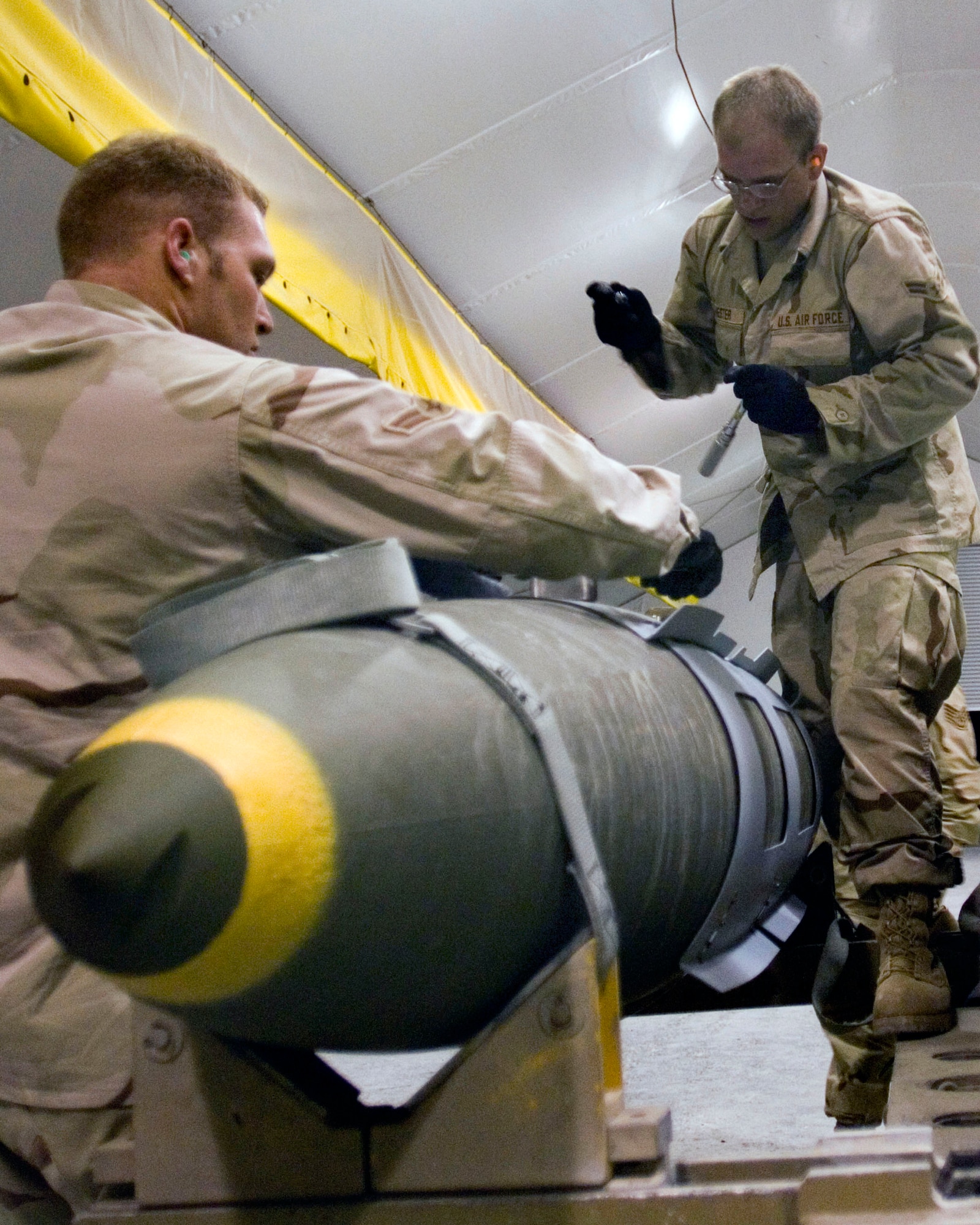 Airmen 1st Class Cory Shinn and Andrew Hester build a GBU-31 bomb to replenish expended munitions.  Both are assigned to the 379th Expeditionary Maintenance Squadron munitions flight. (U.S. Air Force photo\Tech. Sgt. Cecilio Ricardo)