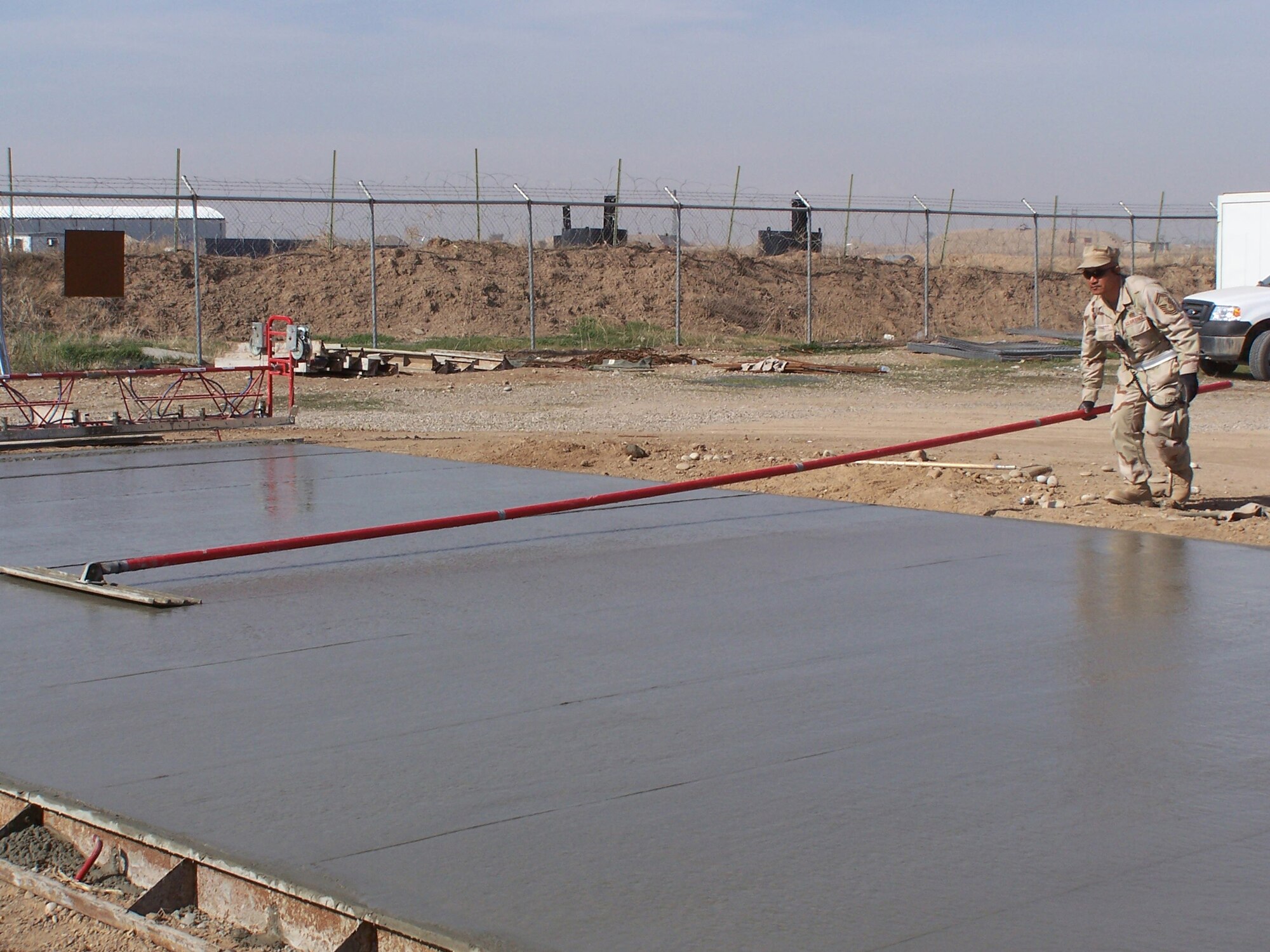 Kirkuk Regional Air Base, Iraq – Senior Master Sgt. Tep Bennett of the 506th Expeditionary Civil Engineer Squadron puts the finishing touches with a bull float on a newly poured concrete pad.  The sergeant is one of more than 60 Air Force reservists deployed to the base from the 445th Civil Engineer Squadron at Wright-Patterson AFB, Ohio. (U.S. Air Force curtsey photo).
