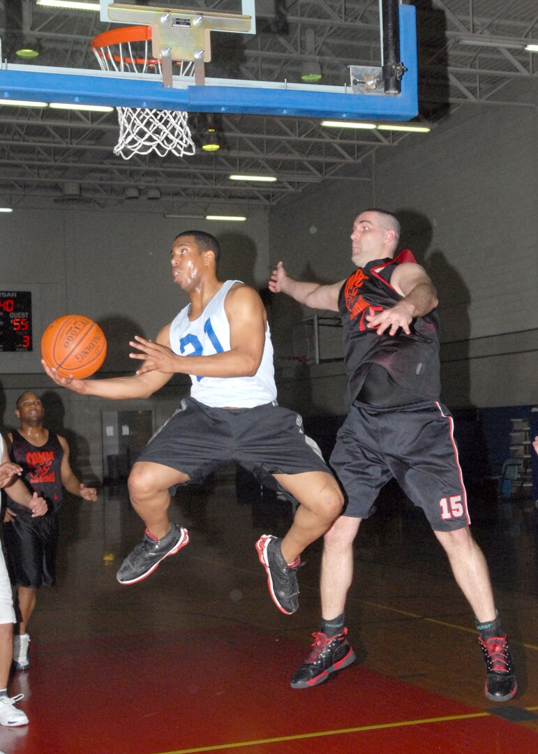 Ryan Nichols (21) from the 737th Training Group leaps for the basket while guarded by Ronald Rhoden from the 37th Communication Squadron Feb. 1 at the Chaparral Fitness Center on Lackland Air Force Base, Texas. TRG defeated COMM 65-57 and moved into a first-place tie at 6-1 with the Air Force Information Operations Center in Division I (National League) base intramurals. TRG and AFIOC will battle each for first-place supremacy 7 p.m. Feb. 8 at the Chaparral. (USAF photo by Robbin Cresswell)  
