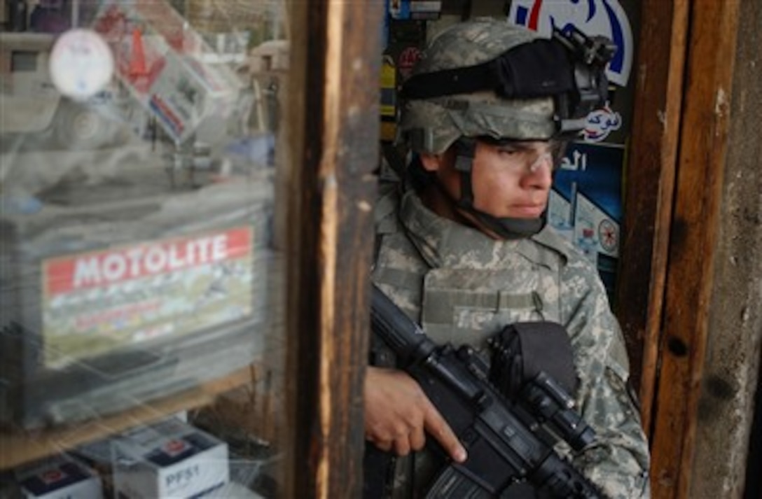 U.S. Army Sgt. Victor Salazar keeps an eye on the street outside while his squad searches a shop in Hateen, Iraq, on Jan. 29, 2007.  Salazar is assigned to Bravo Company, 1st Battalion, 5th Cavalry Regiment, 2nd Brigade Combat Team, 1st Cavalry Division.  