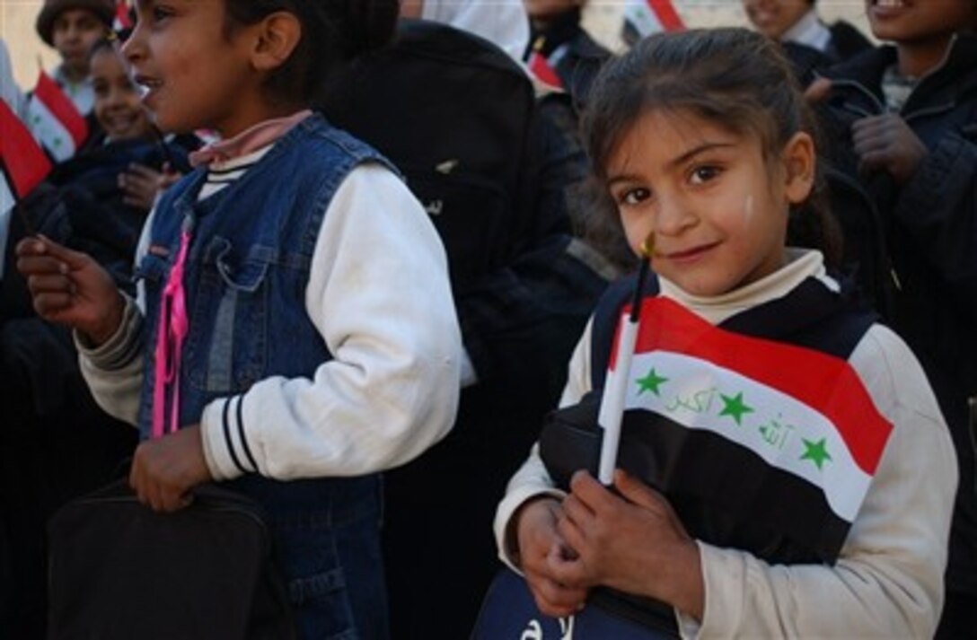 Iraqi school children at the Risalah School wave Iraqi flags and while holding their new book bags courtesy of Iraqi national policemen from the Bayaa Iraqi Police Station. The Iraqi police conducted a school supply mission in the Risalah district of southwest Baghdad, Jan. 24, 2007.