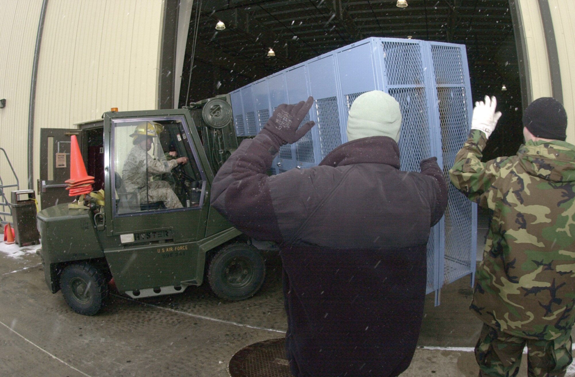 Marine Gunnery Sgt. Adan Moreno, 312th Training Squadron instructor, uses a forklift to transport lockers into the fire academy high bay Tuesday.  Servicemembers to the right provided Gunnery Sgt. Moreno with directions during the move.  (U.S. Air Force photo by Airman 1st Class Luis Loza Gutierrez)