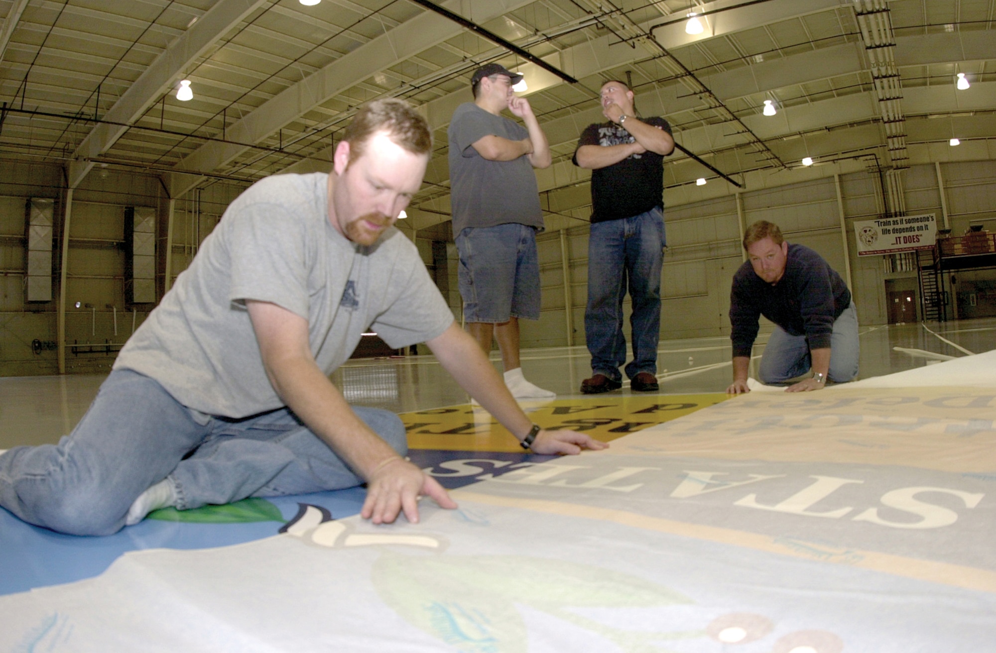 Will Charlesworth (far right) and Travis Turner, co-owners of All About Signs, lay down another section of the large decal now located on the west side of the Louis F. Garland Department of Defense Fire Academy high bay Jan. 12, 2007.  Decal installers Perry Dominguez (wearing baseball cap) and Carlos Carillo stand in the background.  The decal is of the official emblem for Fire & Emergency Services under the Department of Defense.  The decal has a radius of 25 feet.

The decal is part of the renovation done to the fire academy high bay, which began Dec. 31, 2006 and was completed Jan. 13, 2007.  (U.S. Air Force photo by Airman 1st Class Luis Loza Gutierrez)