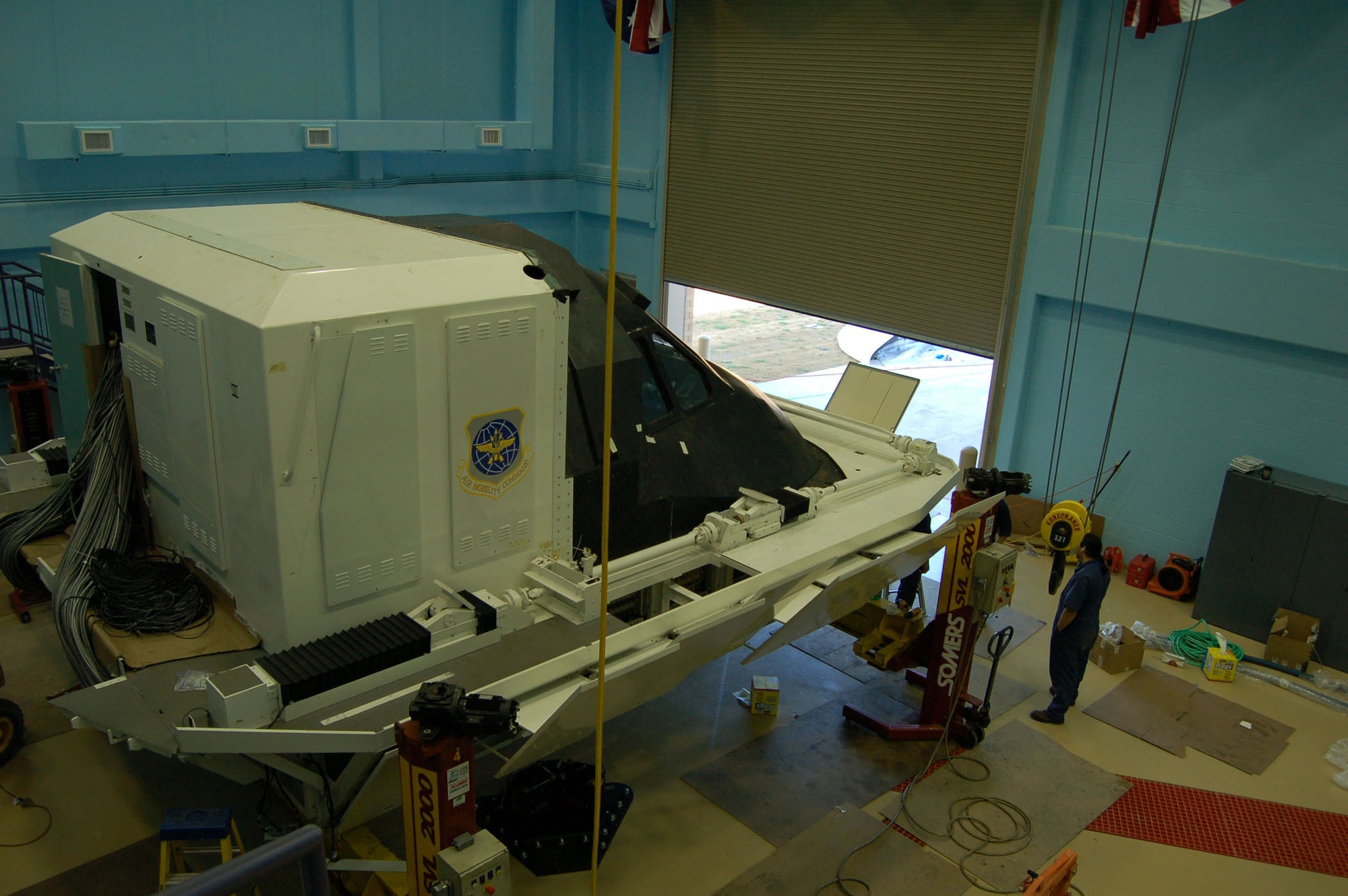 While the C-5 Formal Training Unit at Lackland AFB's Kelly Field held a ceremony to welcome two new squadrons into the 433rd Airlift Wing, The first of the C-5 full motion flight simulators was in the begining stages of instalation. Currently aircrew students and instructors use a simulator in another building within the wing. Once this equipment is up and running, available training time will double for students to earn thier initial qualification, the instructors at the schoolhouse who must maintain thier certification and the 68th Airlift Squadron, the Alamo Wing's operational flying squadron. (U.S. Air Force Photo/Master Sgt. Collen McGee)