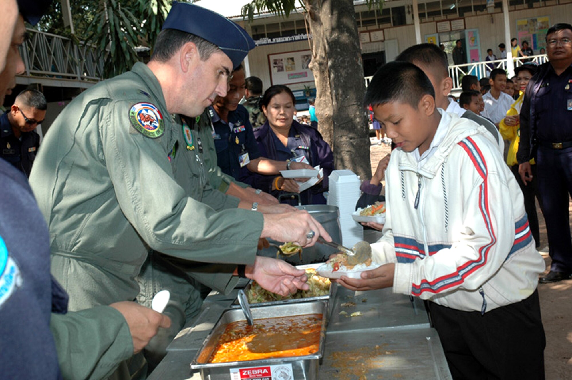 Col. Vincent Farrell serves a spoonful of curry to young Thai students from Ban Chaimongkon School Jan. 30 in Korat, Thailand. Military members from the United States, Thailand and Republic of Singapore took part in a humanitarian mission at the school as part of the multilateral exercise. Colonel Farrell is the 13th Air Force director of air, space and information operations and Air Force working group leader for Exercise Cope Tiger 2007. (U.S. Air Force photo/Staff Sgt. Betty Squatrito-Martin)