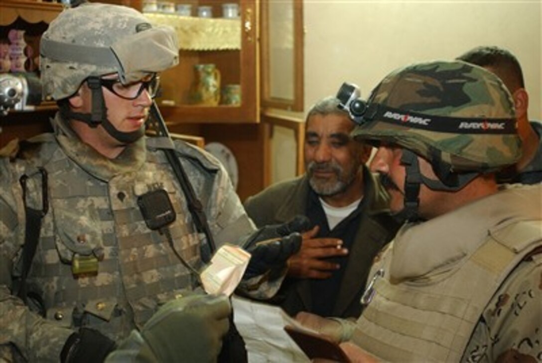 U.S. Army Spc. Michael Wiehe, speaks with an Iraqi Army officer about the items found while searching a home during a combined mission with the Iraqi army in Ghazaliya, Iraq, Jan. 27, 2007.