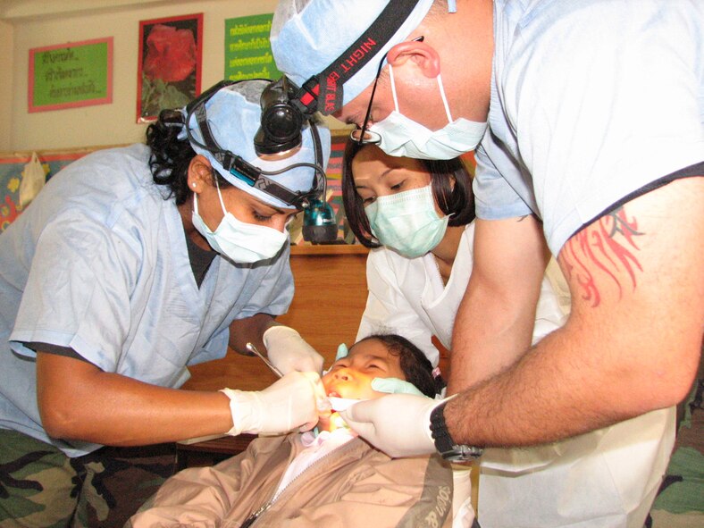 Capt. Ketu Lincoln (L), and Senior Airman Joel Peace (R), 18th Aeromedical Dental Squadron, Kadena Air Base, Japan work to extract a tooth from 8 year old Apiwat Kitjumgnong during a medical-dental goodwill mission at the Thairat 72 school in Udon Thani Thailand Feb. 6. They were there as part of Exercise Cope Tiger 07. (Photo by Army Sergeant Catherine Talento)