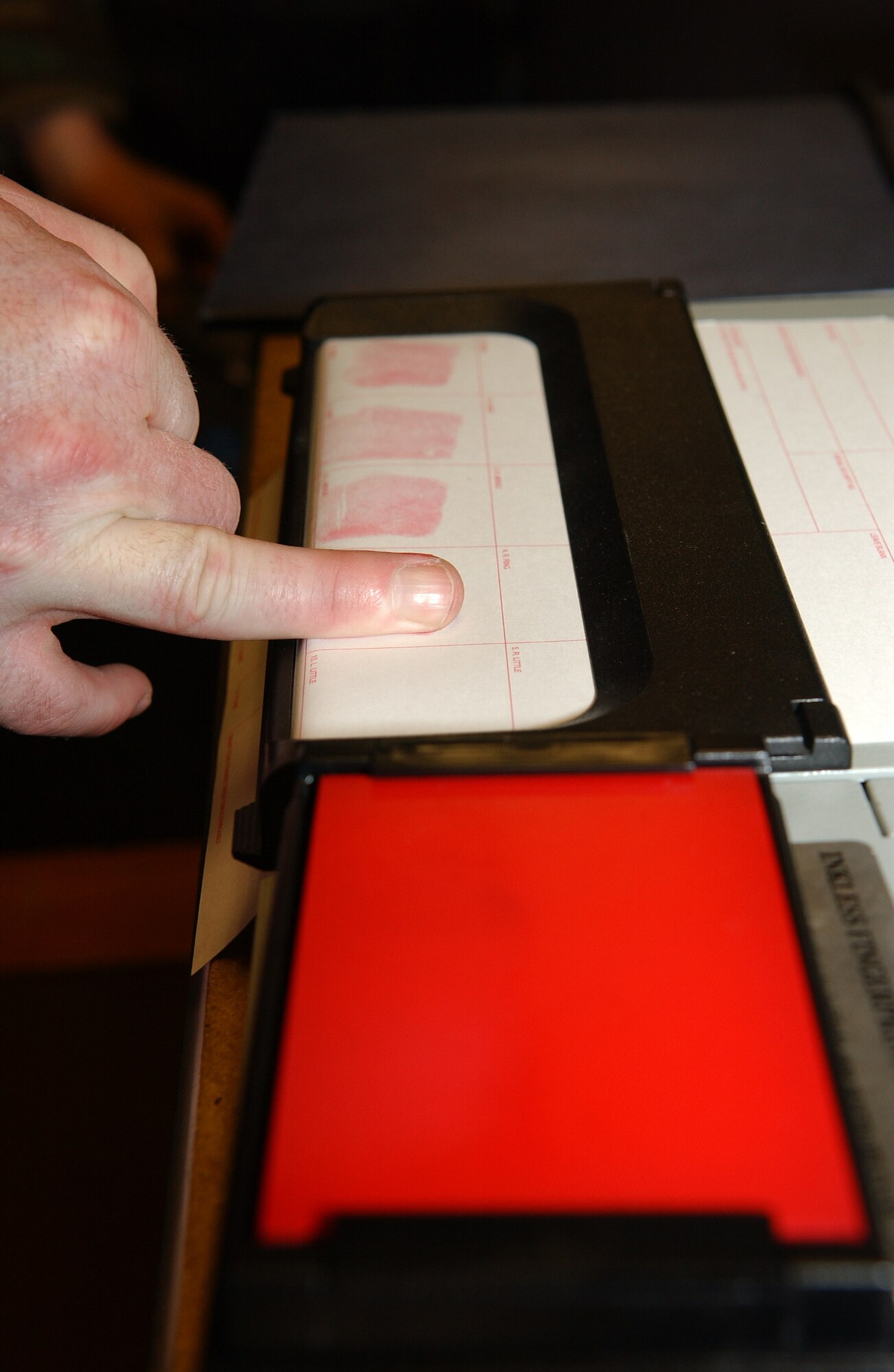 EIELSON AIR FORCE BASE, ALASKA--Investigator Christopher Stone, 354th Security Forces Squadron NCO in charge of investigations, demonstrates fingerprinting by using the inkless fingerprinting system Feb. 2 at the 354th SFS complex. Fingers are placed on the red pad and then on the fingerprint card. Once heat is added to the fingerprint card the prints turn black. (U.S. Air Force Photo by Senior Airman Anthony Nelson)