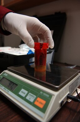 EIELSON AIR FORCE BASE, ALASKA--Investigator Christopher Stone, 354th Security Forces Squadron investigator, weighs a pill bottle containing marijuana. The bottle was recovered on Eielson AFB and catalogued as evidence Feb. 2 at the 354th SFS complex. (U.S. Air Force photo by Senior Airman Anthony Nelson)
