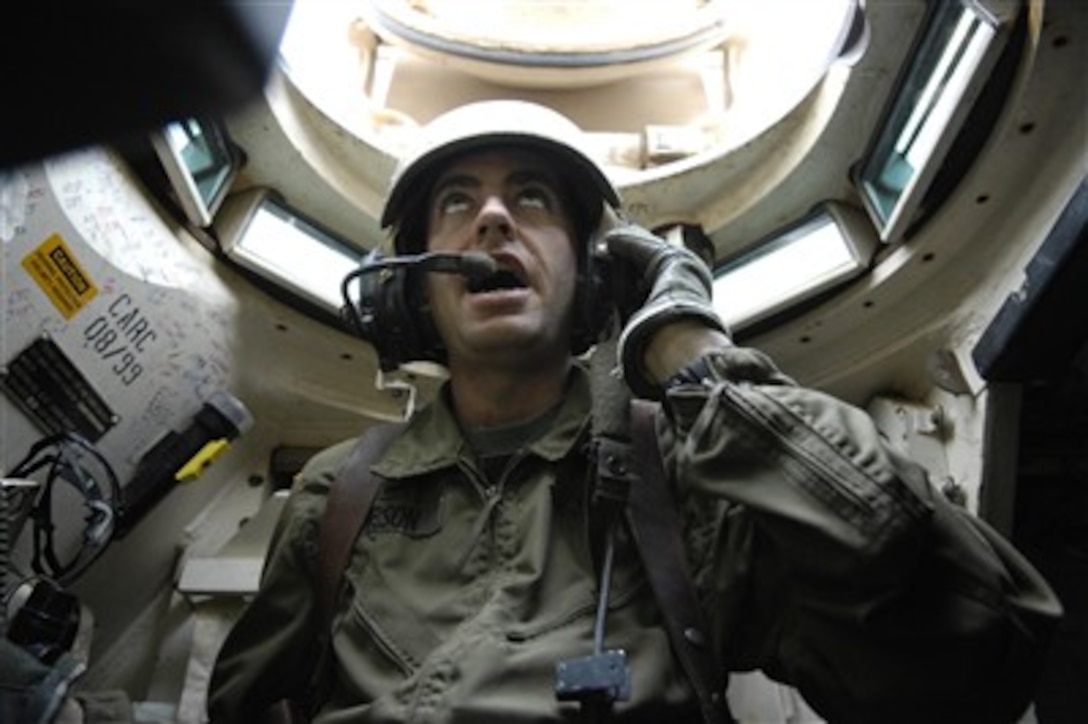 U.S. Army Sgt. 1st Class Michael Gibson directs a convoy of M1A2 Abrams tanks down a road in Kahn Bani Sahd, Iraq, on Feb. 5, 2007.  Gibson is assigned to Charlie Company, 1st Cavalry Division, 12th Infantry Regiment.  