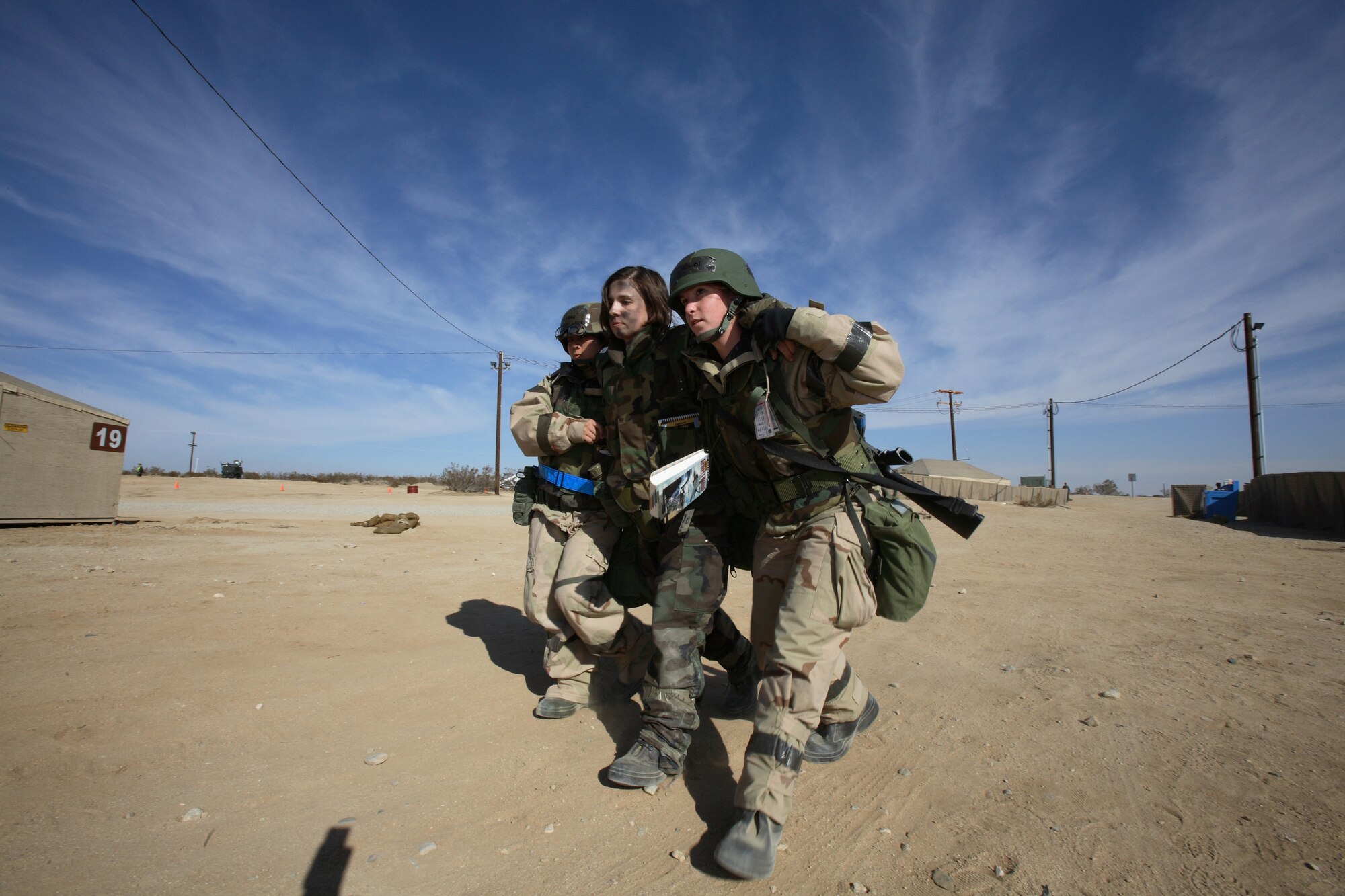 Two Airmen help an injured troop after a simulated attack. (Photo by Jet Fabara)