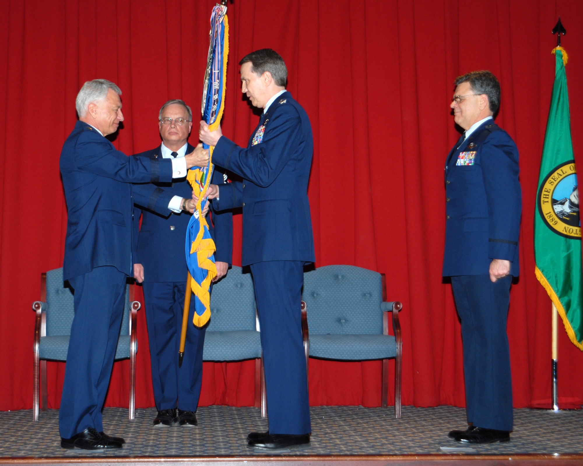 FAIRCHILD AIR FORCE BASE, Wash -- Maj. Gen. Frank Scoggins, Washington Air National Guard commander,  hands the guidon to Col. Gregory Bulkley, 141st Air Refueling Wing commander, while Chief Master Sgt. Craig Weddle, 141st ARW command chief, looks on Saturday. (U.S. Air Force photo by Senior Master Sgt. Bob Thackston)
