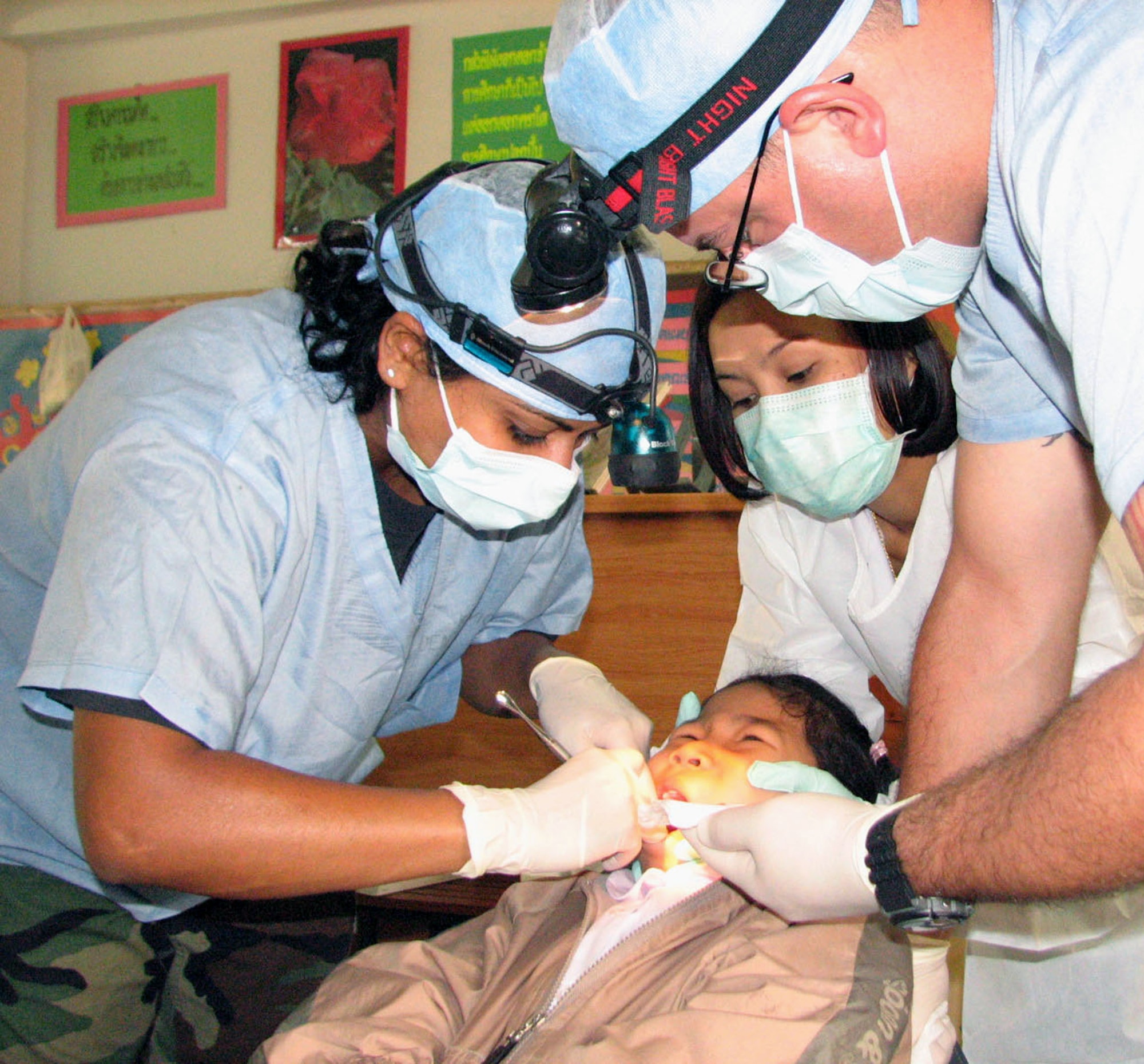 Capt. (Dr.) Ketu Lincoln (left) extracts a tooth from 8-year-old Apiwat Kitjumgnong with assistance from Senior Airman Joel Peace and a Thai dental assistant during a goodwill visit to the Thairat 72 school in Udon Thani, Thailand. This medical-dental goodwill mission is the second civil-action project in Thailand as part of exercise Cope Tiger 2007. Captain Lincoln and Airman Peace are from the 18th Dental Squadron at Kadena Air Base, Japan. (U.S. Air Force photo/Army Sgt. Catherine Talento) 