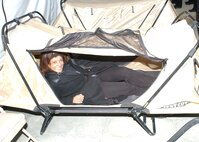 Inside a temper tent at Camp Bullis, Texas, Executive Leadership Development Program student Sheila Barboza, chief of the Communications and Information Career Field Management Office at Randolph Air Force Base, tries out a cot equipped with mosquito netting. The tent is for Airmen going through Lackland's Basic Convoy Combat Course before deploying to Iraq. (USAF photo by Alan Boedeker)                              