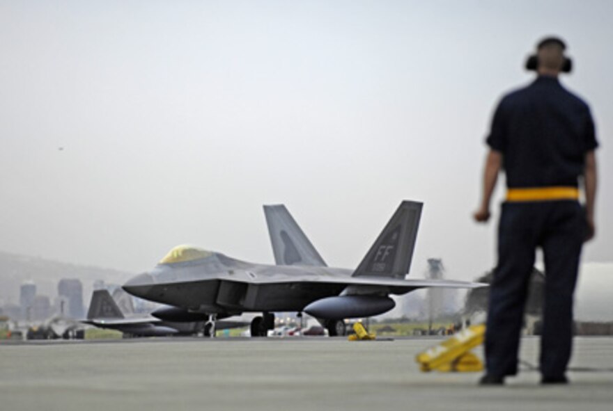 HICKAM AIR FORCE BASE, Hawaii -- A crew chief waits to marshal his F-22 Raptor to its parking spot at Hickam Air Force Base, Hawaii Feb. 7, 2007. The 27th Fighter Squadron, Langley Air Force Base, Va. are deploying 12 F-22s and more than 250 personnel overseas for the first time to Kadena Air Base, Japan. (U.S. Air Force photo/ Tech. Sgt. Shane A. Cuomo)
