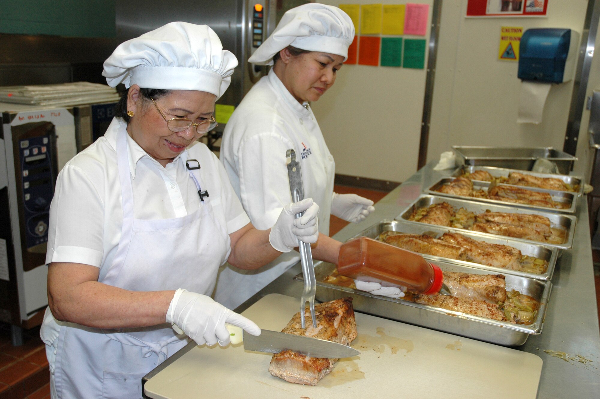 Cooks, Somchit Moslak and Chanphen Duncan, work on dinner for hungry Airmen at the Hillcrest dining facility. Their skills are one of the areas being evaluated for the Hennessy Award. 