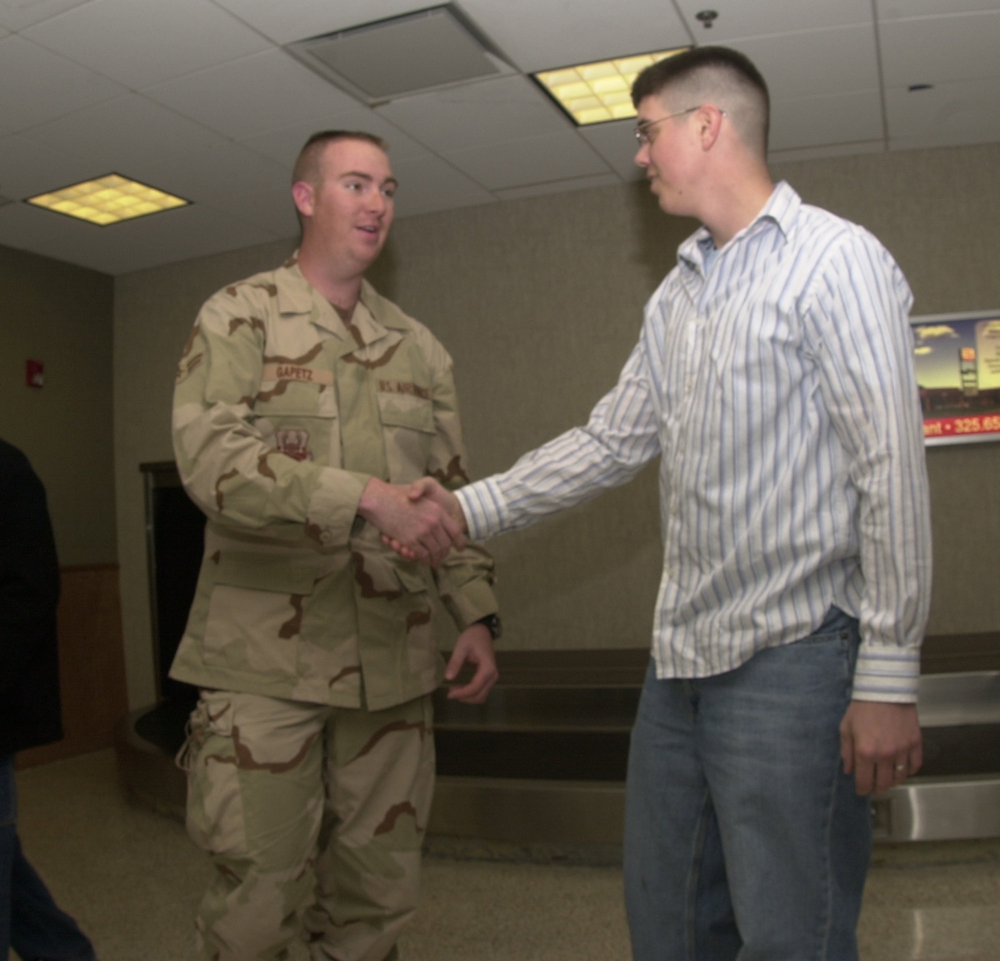 Airman 1st Class Christopher Gapetz (in uniform) is welcomed back home by Senior Airman Brandon Howland, a fellow colleague from the 17th Civil Engineer Squadron Jan. 20, 2007 at San Angelop Regional Airport.  Airman Gapetz was one of more than a dozen deployed servicemembers who returned back to Goodfellow after serving a 120-day tour.  Airman Gapetz was deployed to Ali Al Salem Air Base, Kuwait.  (U.S. Air Force photo by Airman 1st Class Luis Loza Gutierrez)