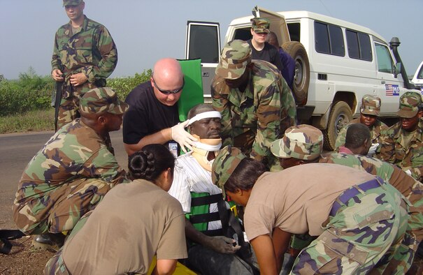 Medics from U.S. Air Forces in Europe, including Senior Master Sgt. Daryl Webb (in sunglasses) and Tech. Sgt. Elizabeth Burrell (black t-shirt), 435th Medical Group, join members of the Armed Forces of Liberia in stabilizing a victim from an auto accident. The AFL members finished learning how to quickly treat and transport victims of trauma moments earlier. (U.S. Air Force photo/Maj. Kimberly Pietszak)