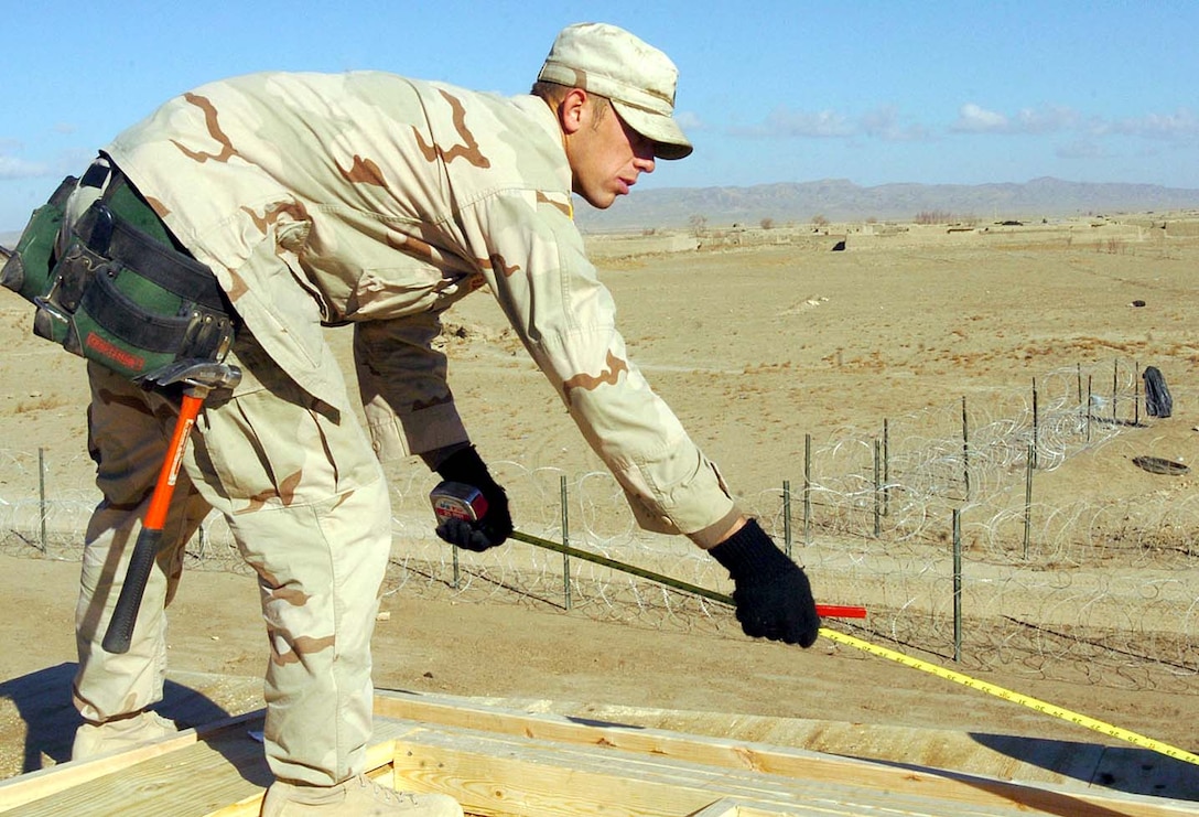 Army Spc. David Baker, a carpenter from the 367th Engineer 
Battalion, uses a tape measure to check the dimensions on a new guard tower at 
Firebase Waza Khwa, Afghanistan. Photo by Staff Sgt. Bradley Rhen, 
USA