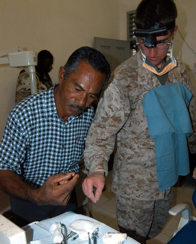 Navy dentist Lt. Chris Hamlin watches as his first patient of  the day, Umar, picks up his tooth that Hamlin extracted. Hamlin is part of a five-person dental team with the MEU Service Support Group  15, a part of the 15th Marine Expeditionary Unit. The team is operating a dental  clinic at the hospital in Meulaboh, Indonesia. Photo by Samantha L. Quigley
