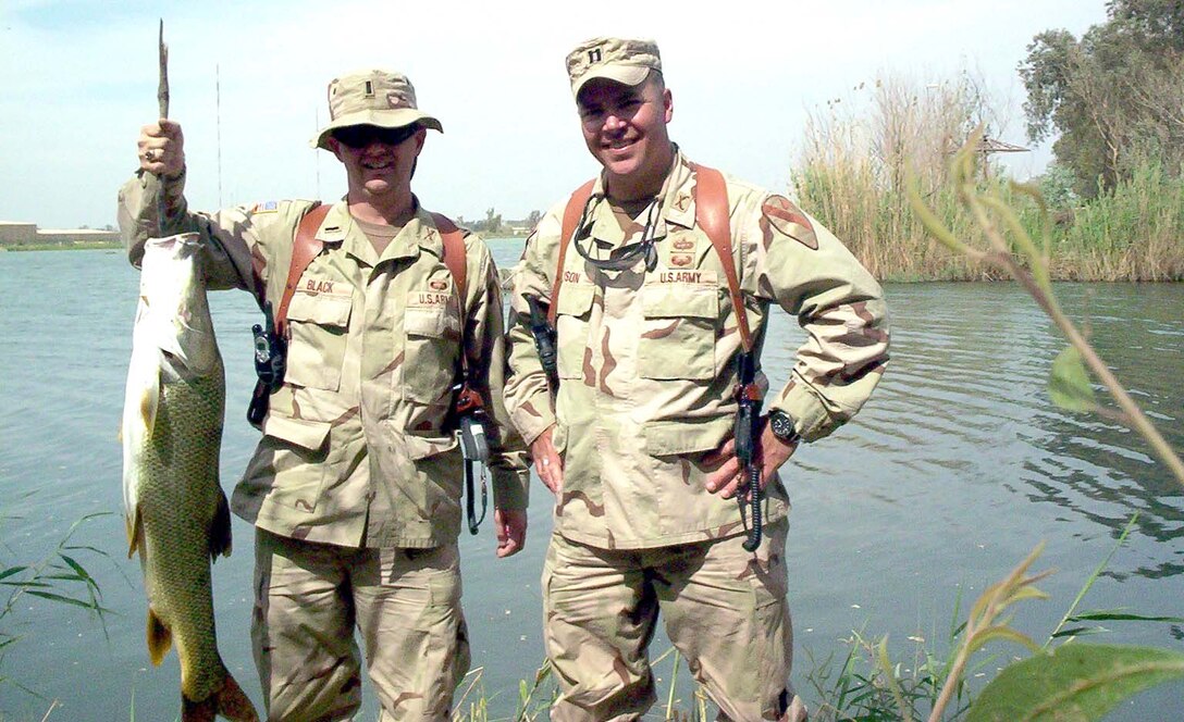 Army 1st Lt. Kevin Black (left), executive officer for 1st Cavalry 
Division's headquarters company, shows off a fish he caught at Camp al-Tahreer in 
Baghdad, Iraq, with Capt. Sean Tyson, headquarters company commander. The fish 
measured in at 38 inches, but the soldiers aren't sure of its species. Photo by Spc. 
Andy Miller, USA