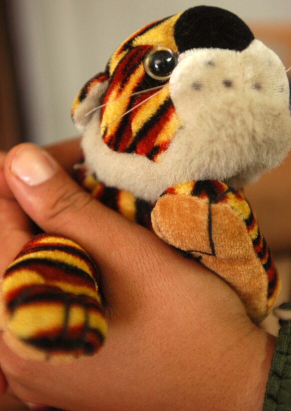 Sally holds onto the stuffed tiger that once belonged to her 5- year-old son. She has not seen her four children in eight months and does not  know where they are. Sally serves as a translator for multinational forces in  Iraq, which has caused her to be beaten and disavowed, and her life has been  threatened by her own family. Every time the 28-year-old leaves for a mission,  she brings this stuffed animal as a reminder of all she has lost and all she  has gained since helping the coalition. She hopes to move to the United States  and continue helping the military. Photo by Cpl. Veronika R. Tuskowski, USMC