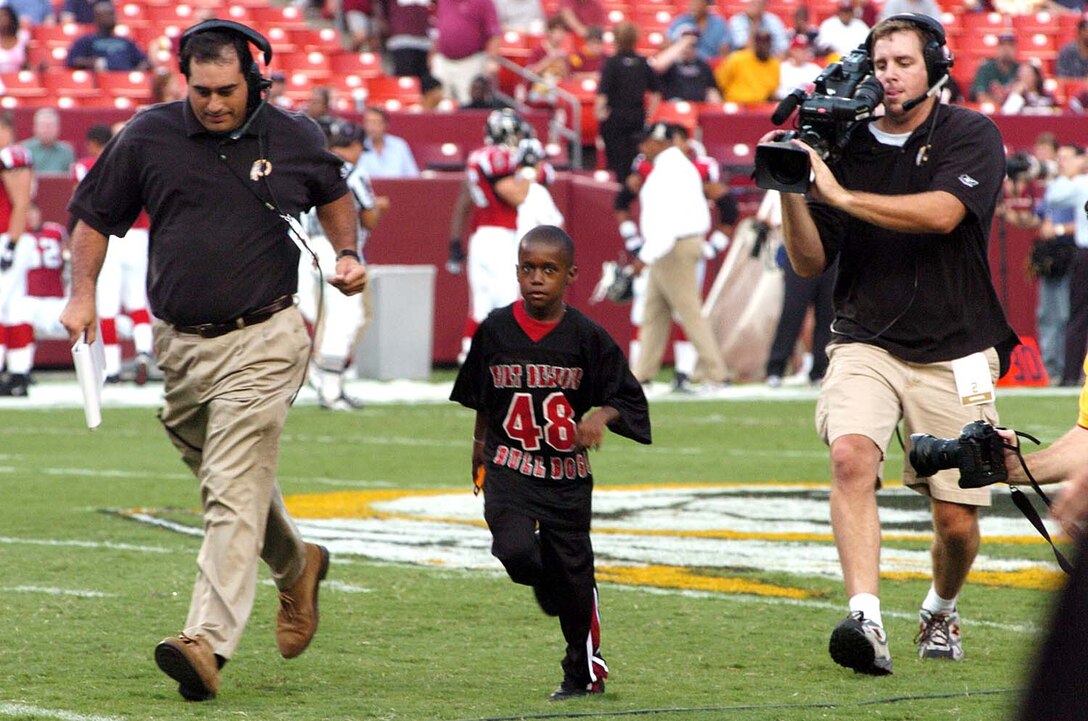 Ricky Morgan Jr., a member of the Fort Belvoir Bulldogs 
anklebiters youth football team and son of Army Sgt. Maj. Ricky Morgan, runs 
off FedEx Field after participating in the coin toss before the Atlanta 
Falcons-Washington Redskins NFL exhibition game Sept. 3 at Landover, Md. Photo 
by Tim Hipps
