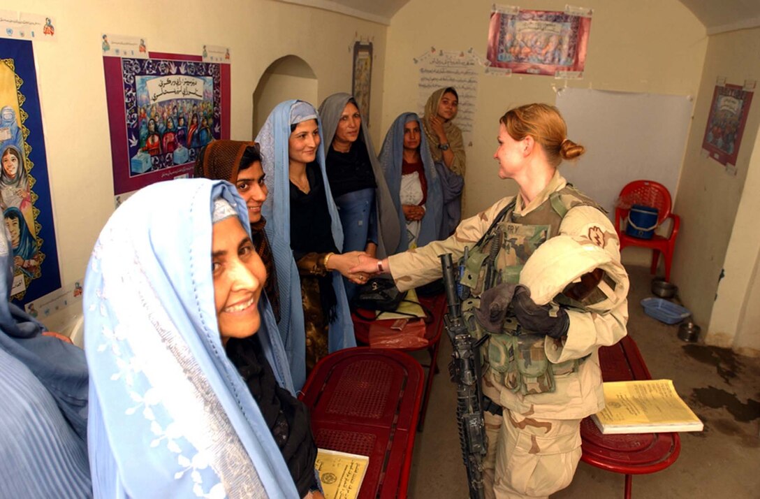 Army Sgt. Jade Fry, a member of the 25th Military Police 
Company, meets with local Afghan women in a voter-registration center in 
Kandahar, Afghanistan. The presence of female soldiers displays to Afghans, 
especially the women, America's resolve as a democracy to give equal rights to 
all its citizens. Photo by Sgt. Frank Magni, USA