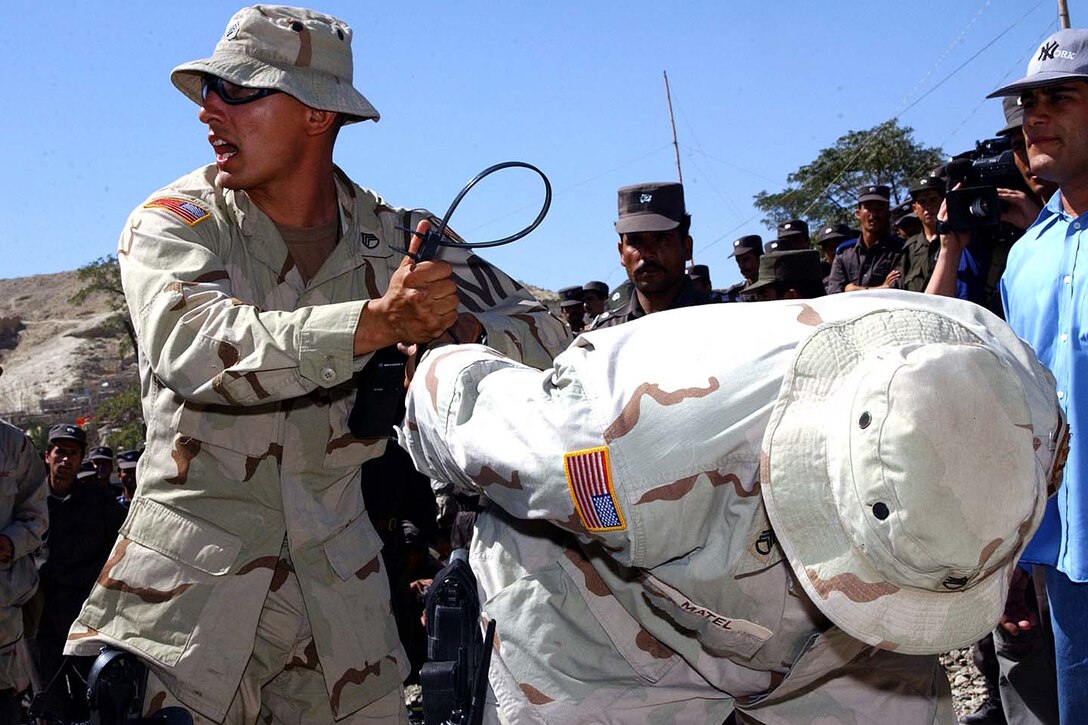 U.S. Army Staff Sgt. Damiam George, of the 58th Military 
Police Company stationed at Bagram Air Base, demonstrates to Afghan National 
Police officers the proper way to handcuff a suspect as part of a training 
exercise in the use of modern police tactics.  Photo by Sgt. 1st Class Darren 
D. Heusel, USA