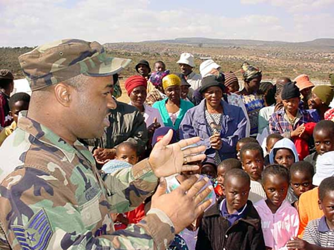 U.S. Air Force Tech. Sgt. Victor D. Grubbs, a member of 3rd 
Air Force from the Royal Air Force base at Mildenhall, England, leads and 
teaches a spiritual song to the children of the Kgautswane Community 
Development Center in Kgautswane, South Africa, July 10. Air Force personnel, 
deployed to South Africa forthe MedFlag 2004, assisted in delivering donations 
to the children of theKgautswane Community Development Center. Members of the 
48th Medical Groupcollected eight boxes of donations before deploying to South 
Africa in early July. Photo by Master Sgt. Doris Libby, USAF