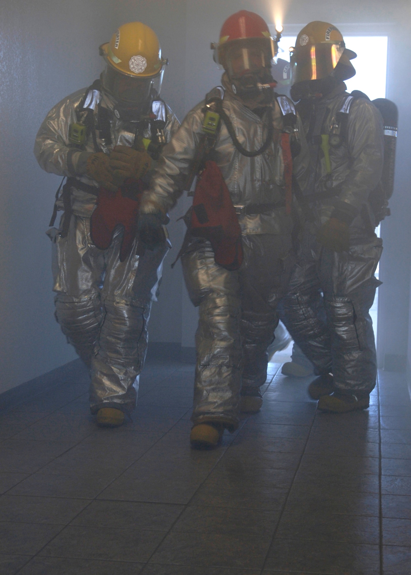 Senior Airman Michael Lewis, Airman 1st Class Robert Whitaker and Tech. Sgt. Steven Nordlund begin to open doorways for ventilation during a simulated fire and evacuation at Davis-Monthan Air Force Base, Ariz., in preparation for an operational readiness inspection. The three Airmen are firefighters assigned to the 355th Civil Engineer Squadron. (U.S. Air Force photo/Senior Airman Christina D. Ponte)
