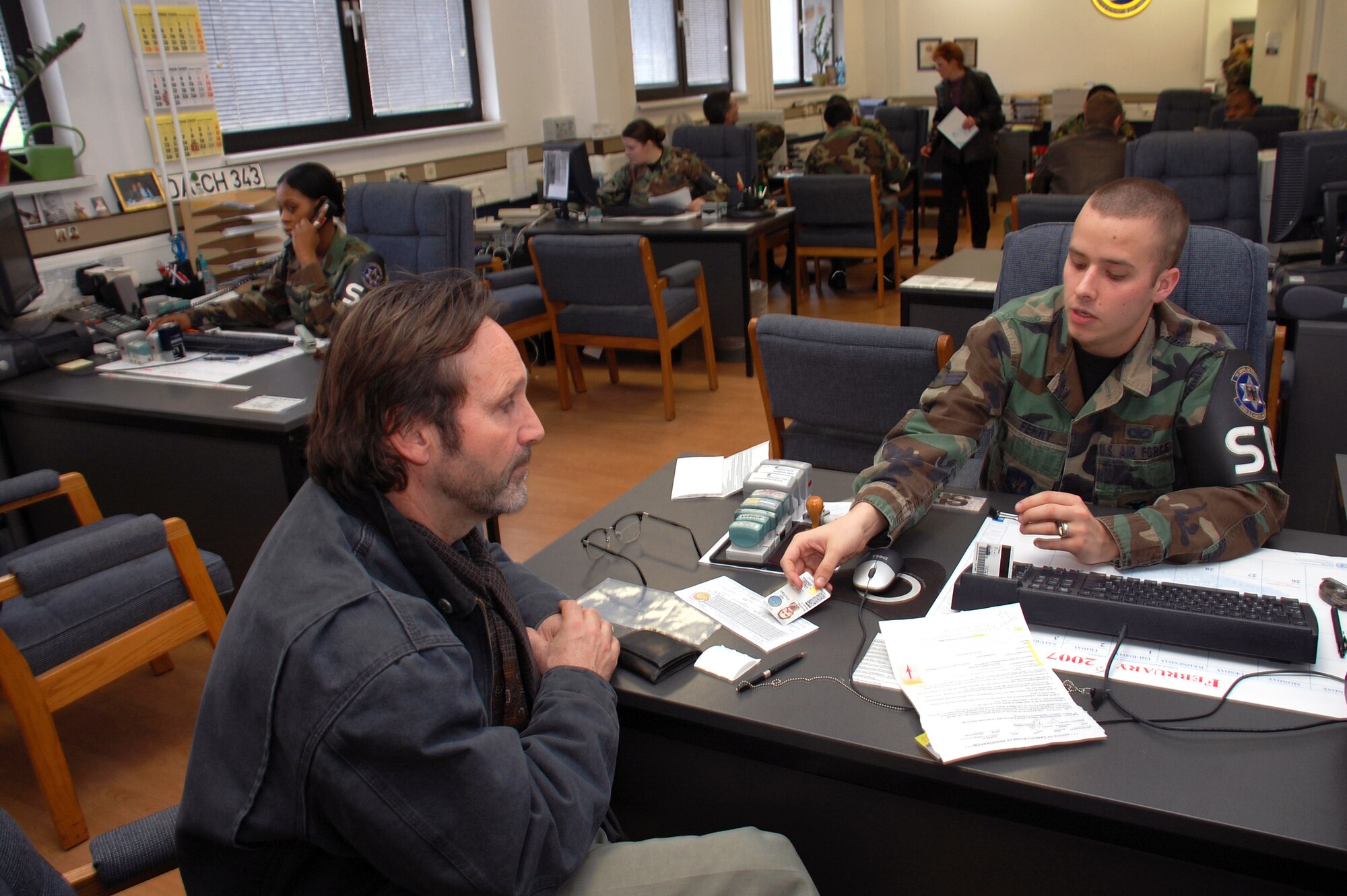 Grant Hrushka speaks with Airman 1st Class Alan Ferry in the vehicle registration office Feb. 1 at Kaupaun Air Station, Germany. The vehicle registration team serves approximately 50,000 people, including Mr. Hrushka who is a Department of Defense Dependent Schools teacher. (U.S. Air Force photo/Staff Sgt. Dan Bellis) 