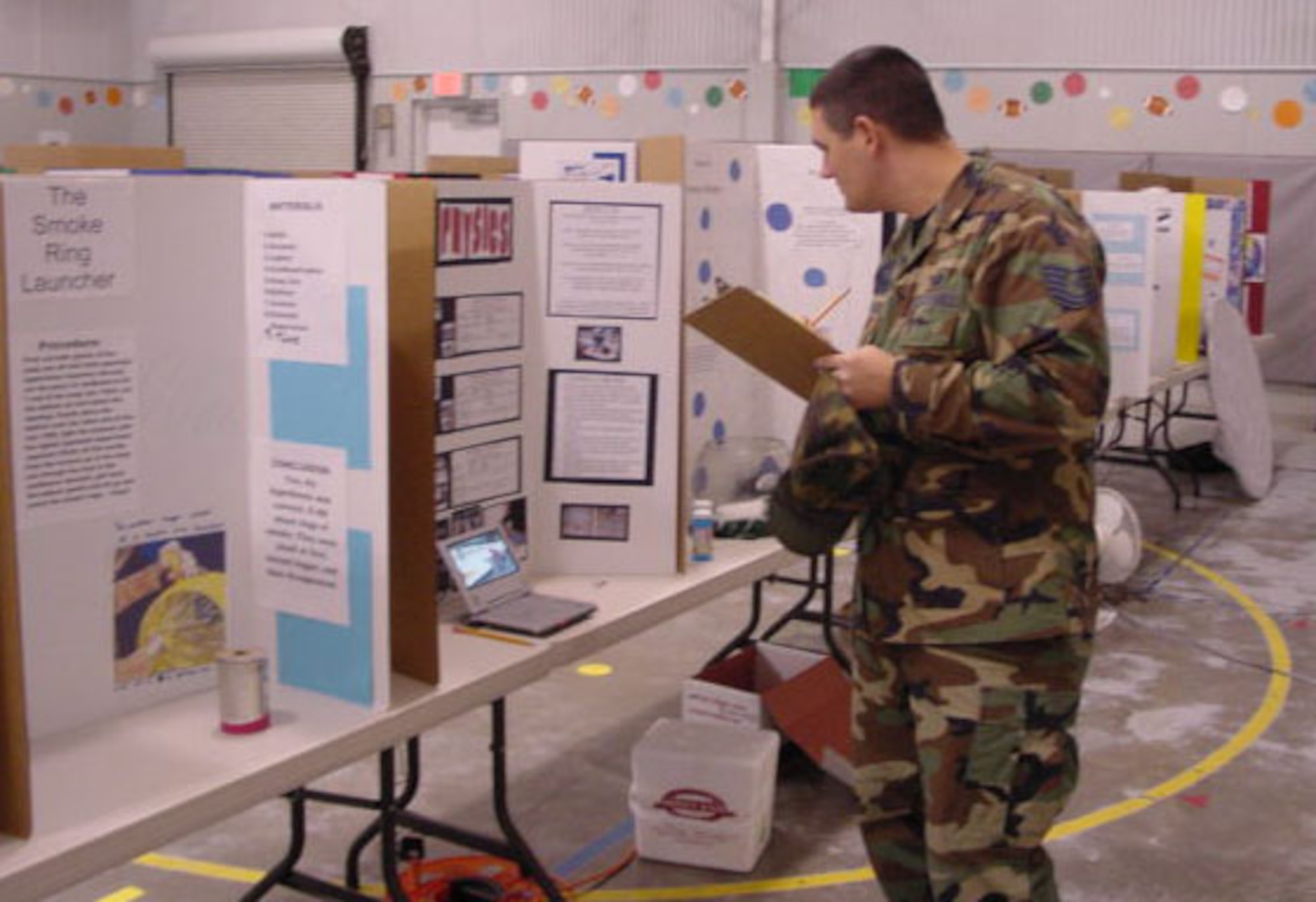 Tech. Sgt. Joshua Tulloch, 316th Training Squadron, reviews a sixth grader’s display discussing the physics of hovercraft operations. (U.S. Air Force photo by Tech. Sgt. Kelly Bales)