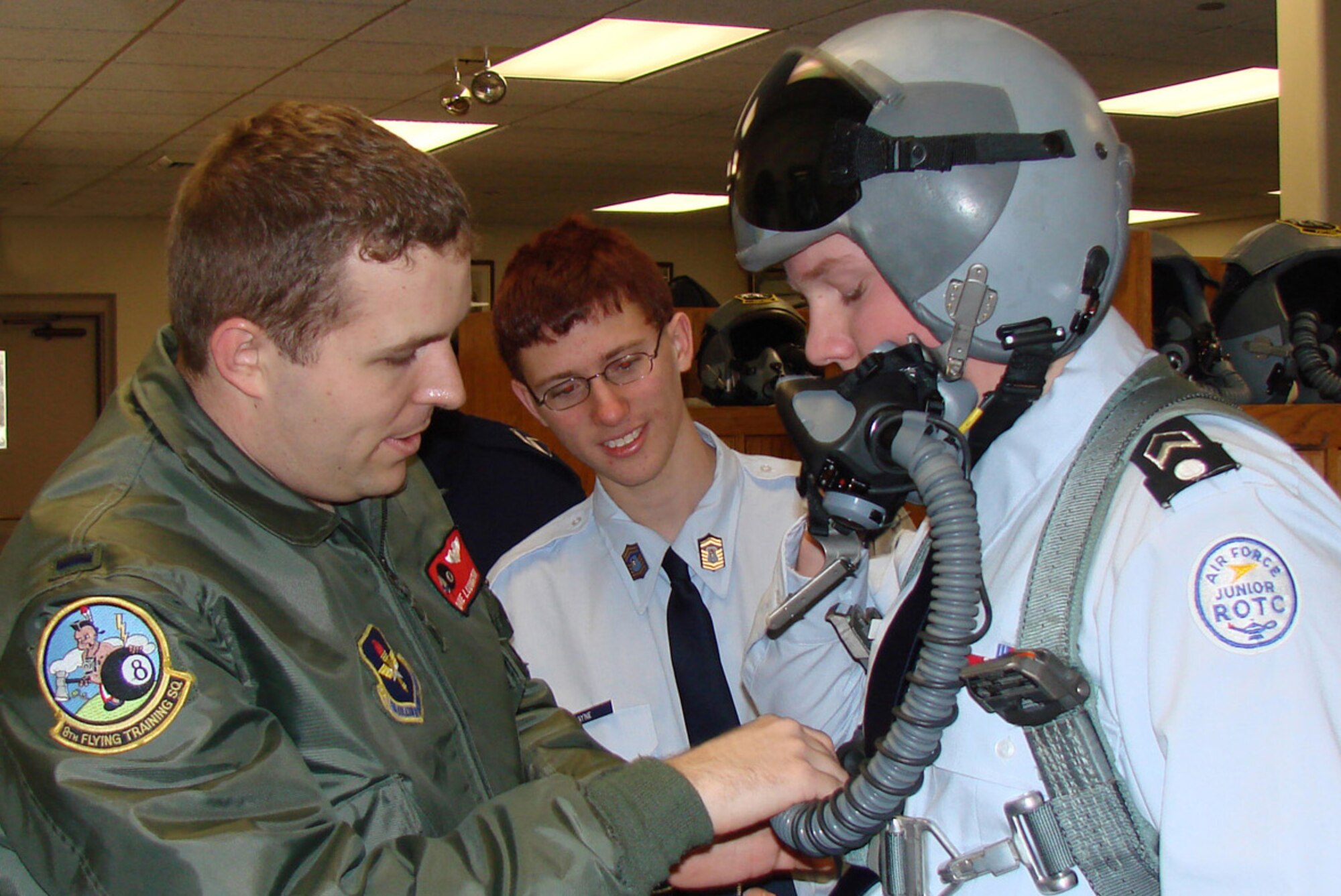 First Lt. Dave Ludington, 8th Flying Training Squadron instructor pilot, demonstrates an oxygen mask connection to Junior ROTC cadet Alex Owen while cadet William Payne looks on. Cadets from the Enid (Okla.) High School Junior ROTC detatchment visted the 8th FTS at Vance Air Force Base Feb. 8 as part of the squadron's heritage week Feb. 7 to 14. The event is part of Vance's year-long commemoration of the Air Force's 60th anniversary. (Photo by 2nd Lt. Agneta Murnan)       
