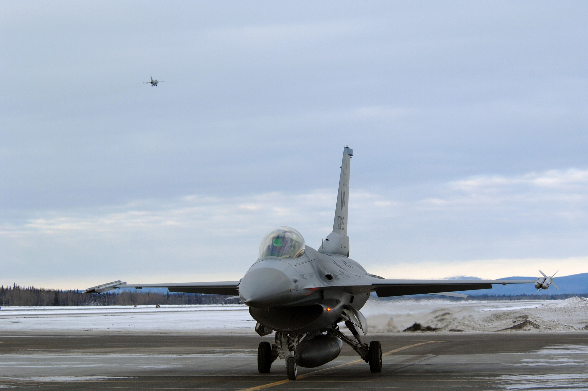 EIELSON AIR FORCE BASE, Alaska -- An F-16C Fighting Falcon aircraft from the 18th Fighter Squadron waits to taxi while another F-16 aircraft takes off in the background for a training mission here on Feb.8. The 18th Fighter Squadron conducts air operations for combat-ready F-16 aircraft and provides close air support, forward air control (airborne), battlefield air interdiction, and offensive counter air.
(U.S. Air Force Photo by Staff Sgt Joshua Strang)