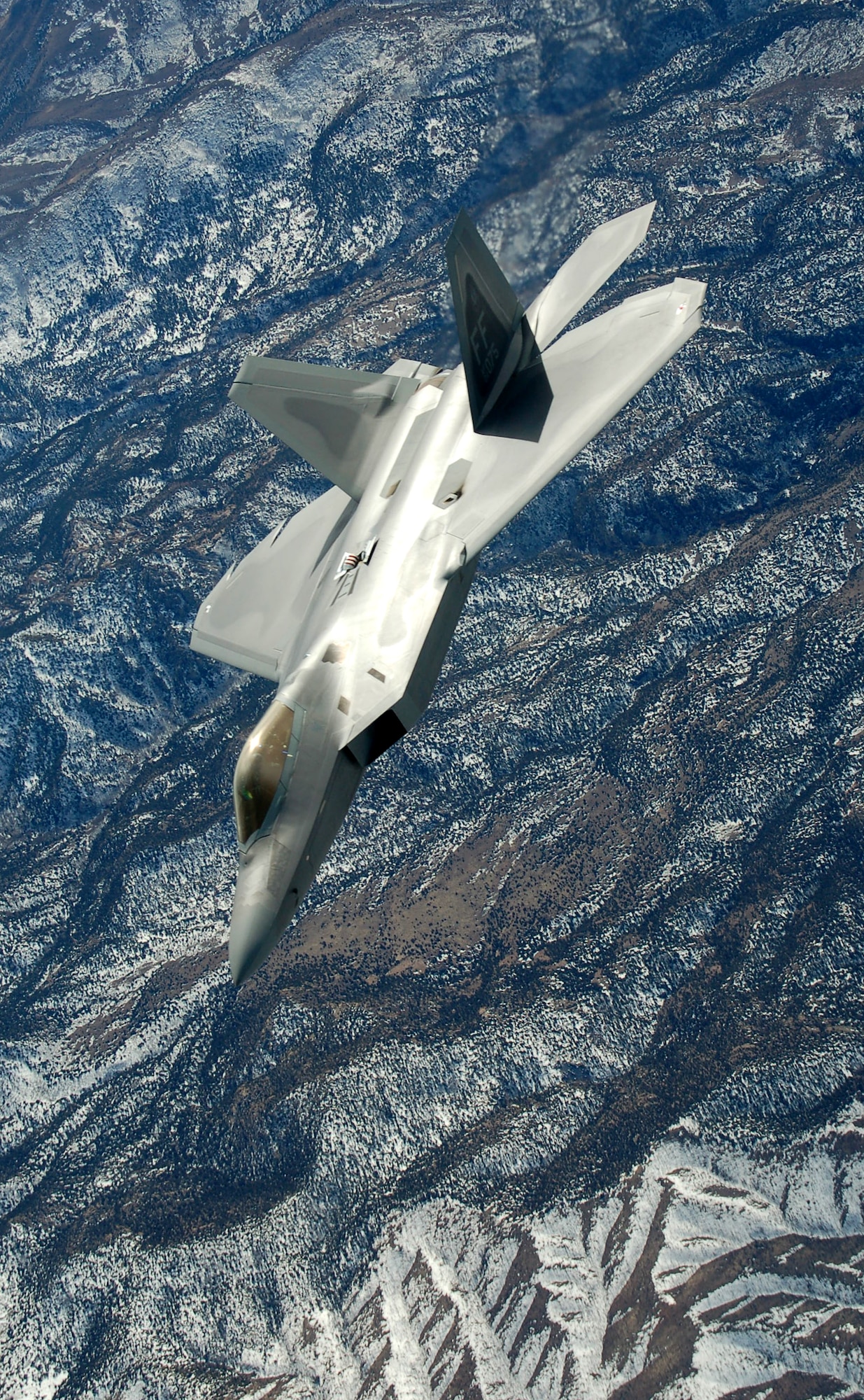 An F-22 Raptor flies off after being refueled by a KC-135 Stratotanker during the Red Flag exercise Feb 7 at Nellis Air Force Base, Nev. The two KC-135 Stratotankers from the 319th Air Refueling Wing at Grand Forks Air Force Base, N.D., make up the lead tanker unit during the exercise. Red Flag is an exercise designed to hone the warfighting skills of Air Force pilots for conflicts. (U.S. Air Force photo/1st Lt. Randi Norton)