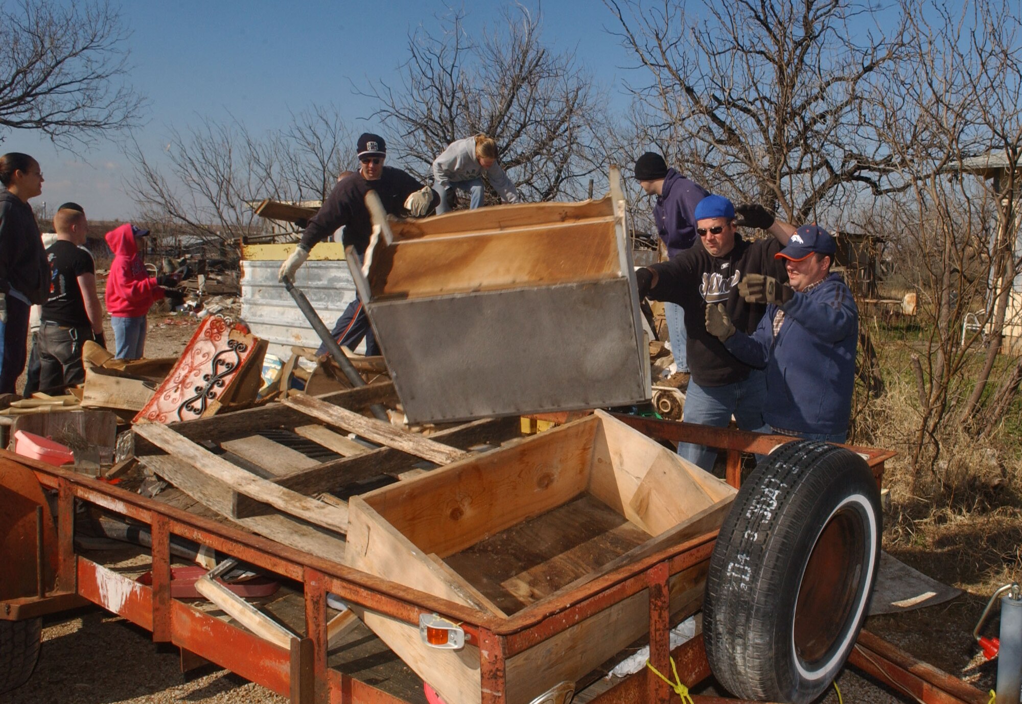 Volunteers toss rubbish onto another trailer during the clean-up. Some of the rubbish included large pieces of furniture and rusty appliances. (U.S. Air Force photo by Staff Sgt. Gina O’Bryan)