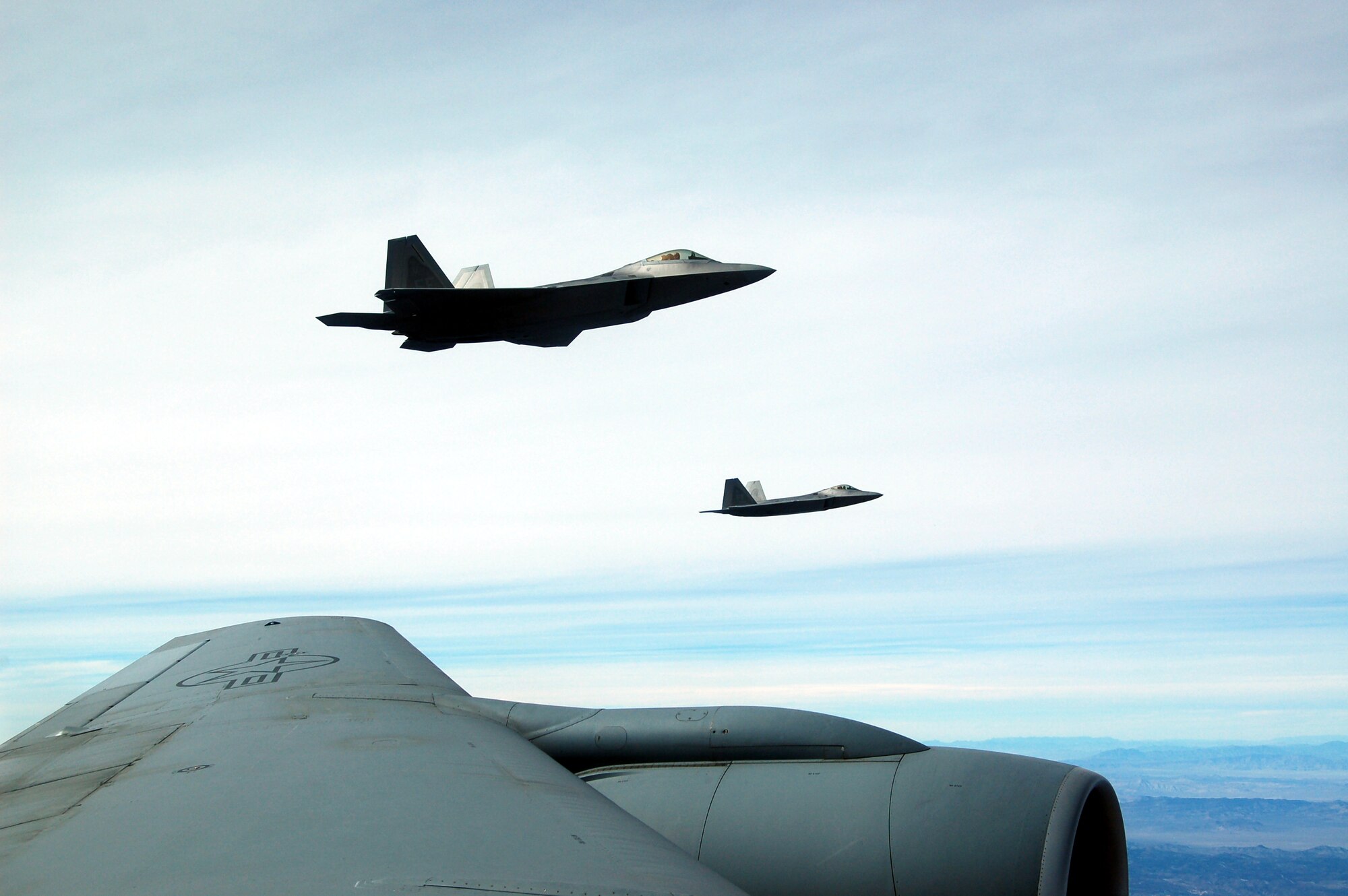 NELLIS AIR FORCE BASE, Nev. -- Two F-22A Raptors fly off the left wing of a Grand Forks Air Force Base KC-135 during the Red Flag Exercise  Feb 7. Two KC-135 Stratotankers from the 319th Air Refueling Wing are the lead tanker unit during the exercise. Red Flag is an exercise designed to hone the war-fighting skills of Air Force pilots for current and future conflicts. (U.S. Air Force photo/1st Lt. Randi Norton)

