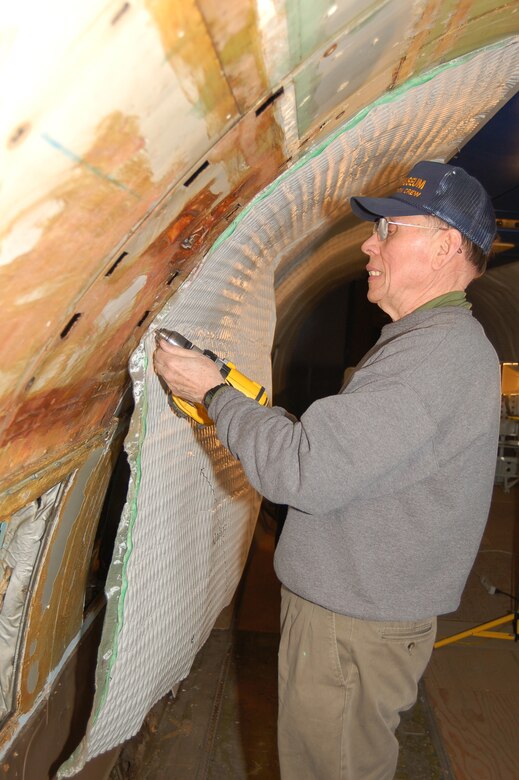Larry Phillips, Air Mobility Command restoration crew member and retired Air Force C-133 pilot, attaches padding to interior of Lockheed C-121 Constellation currently under renovation. (U.S. Air Force photo/Tech. Sgt. Kevin Wallace)
