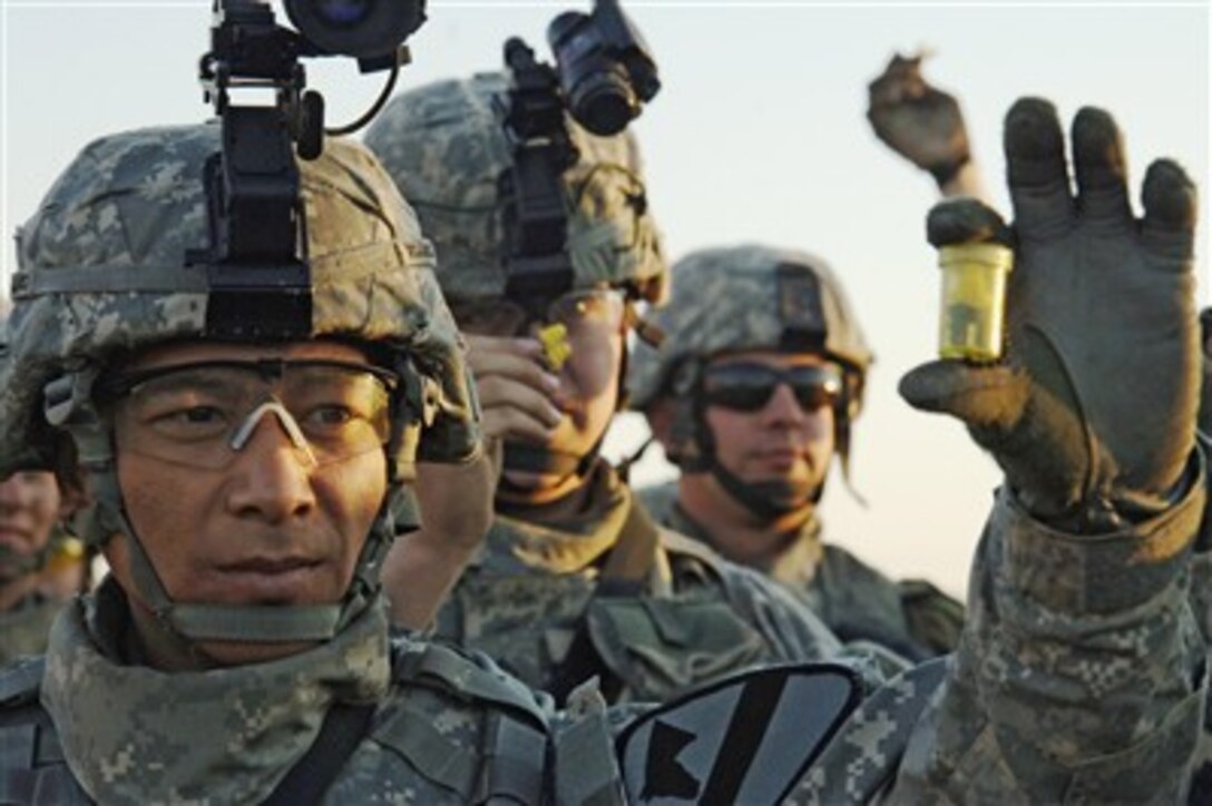 U.S. Army Pfc. Douglas Wojtowicz and fellow soldiers from the 2nd Battalion, 8th Cavalry Regiment show their combat ear plugs during a pre-combat check at Camp Taji, Iraq, on Feb. 7, 2007, prior to conducting a night mission.  