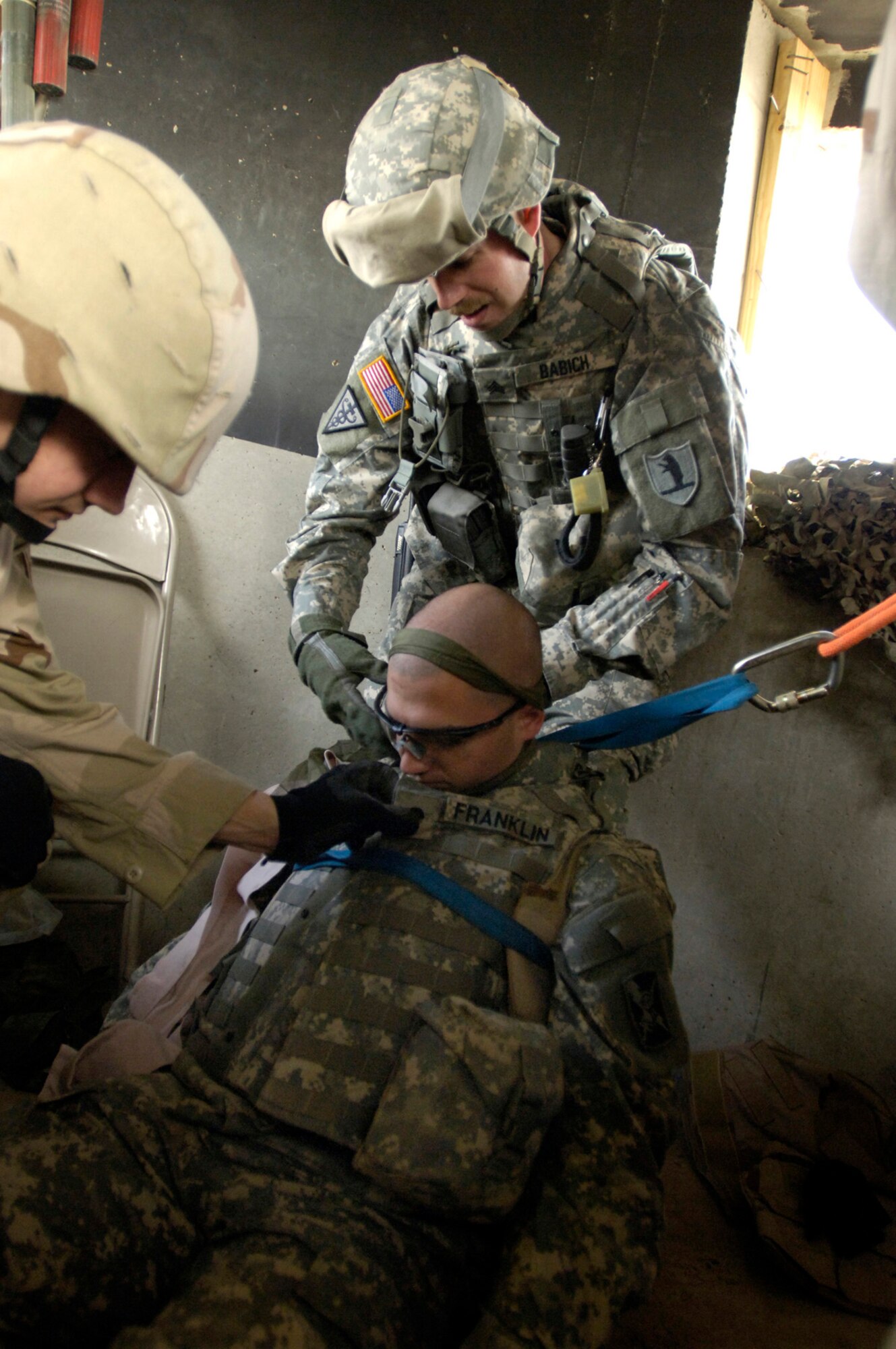 Balad Air Base, Iraq -- After assessing the wounded soldier's situation, Sgt. Christopher Babich sets Spc. Franklin up in a harness-pulley system to lower him down the watch tower during the perimeter tower rescue exercise, Feb. 9.  This joint exercise evaluates the emergency response time and skills of the 332nd Expeditionary Civil Engineer Squadron fire department, the 60th Ordinance Company, and 206th Army Support Medical Company. Sgt Christopher Babich is with the 206th Army Support Medical Company.  (US Air Force photo/Tech. Sgt. Cecilio Ricardo)(released)