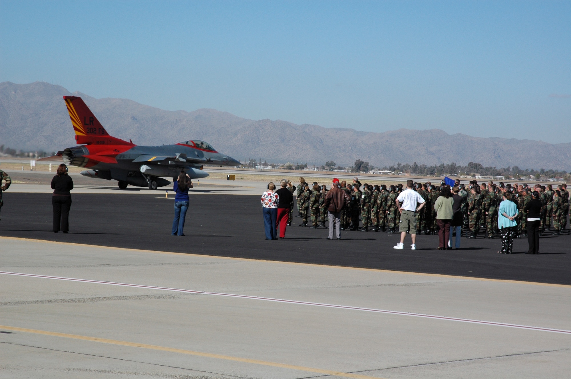 Members of the Air Force Reserve Command's 944th Fighter Wing at Luke Air Force Base, Ariz., watch as the 302nd Fighter Squadron's flagship passes for it's final flight as a 944th Fighter Wing jet. The flagship, painted in Original Tuskegee Airmen colors, will go on to become an aggressor at Nellis Air Force Base, Nev. The 944th Fighter Wing is home to two Original Tuskegee Airmen squadrons, the 301st and 302nd Fighter Squadrons. The 944th Fighter Wing's 17 Fighting Falcons are being reassigned to other units as part of Base Realignment and Closure.  (U.S. Air Force photo/Staff Sgt. Susan Stout)